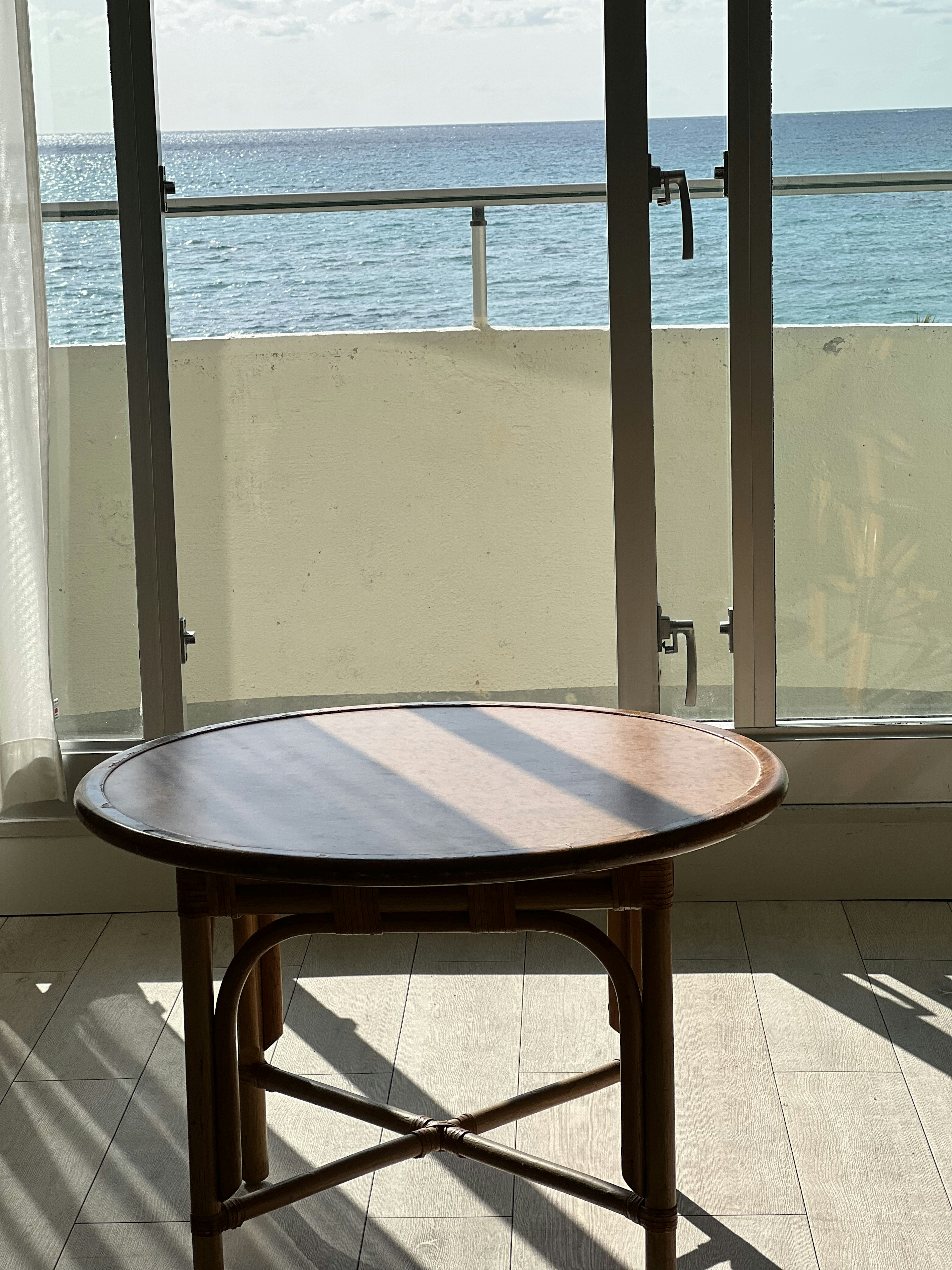 Round wooden table in front of a window with an ocean view