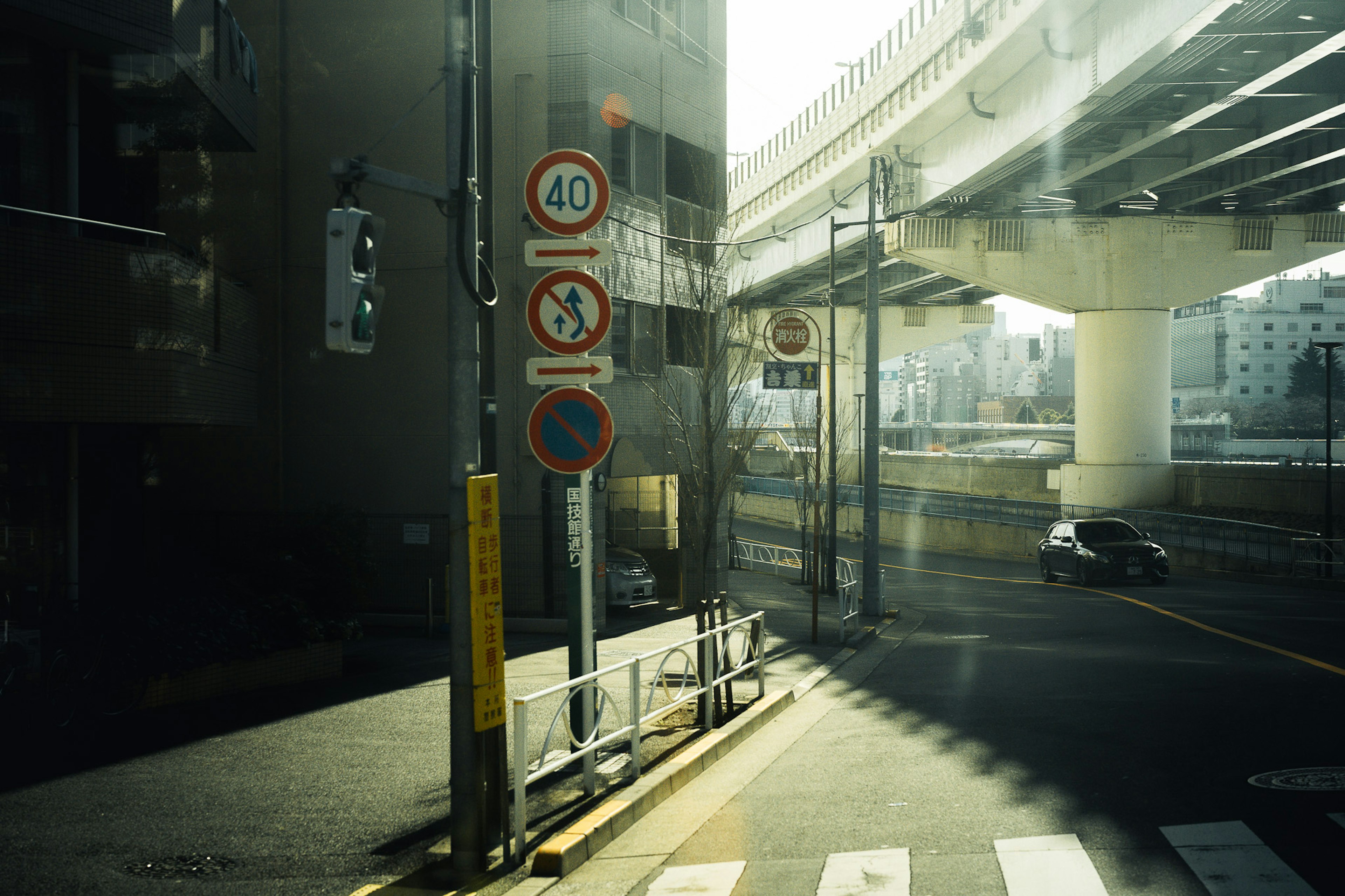 都市の交差点に立つ交通標識と高架道路の風景