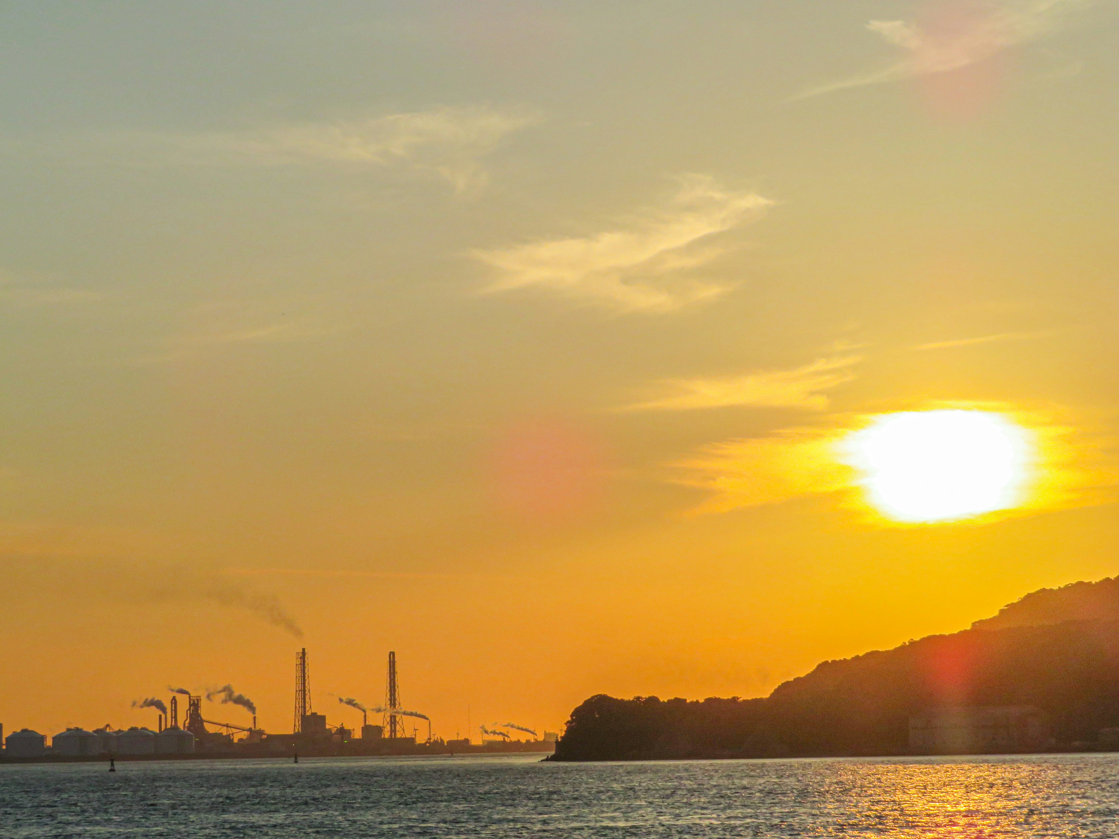 Industrial landscape at sunset with smokestacks and coastline silhouette