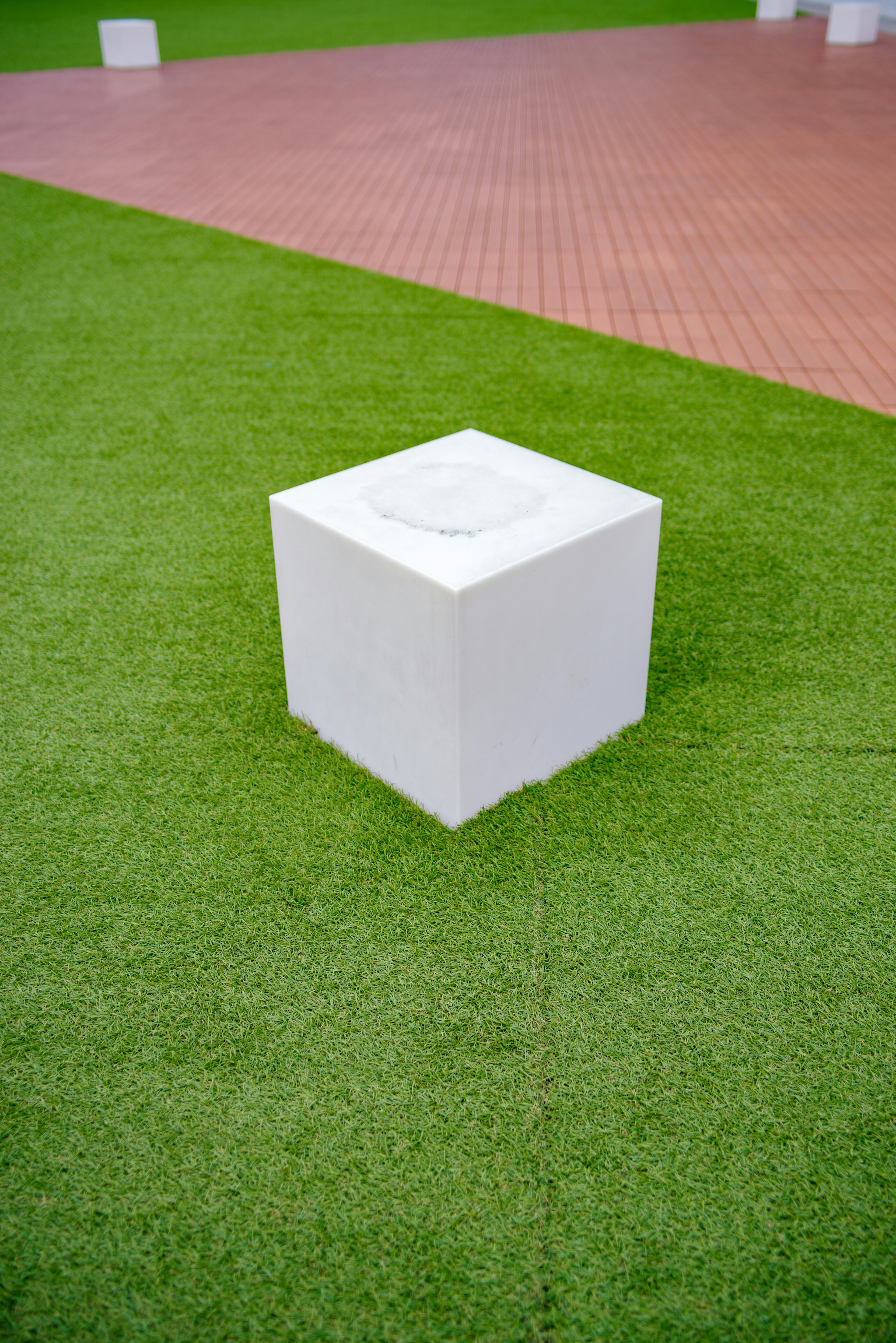 White cube object on green grass surface