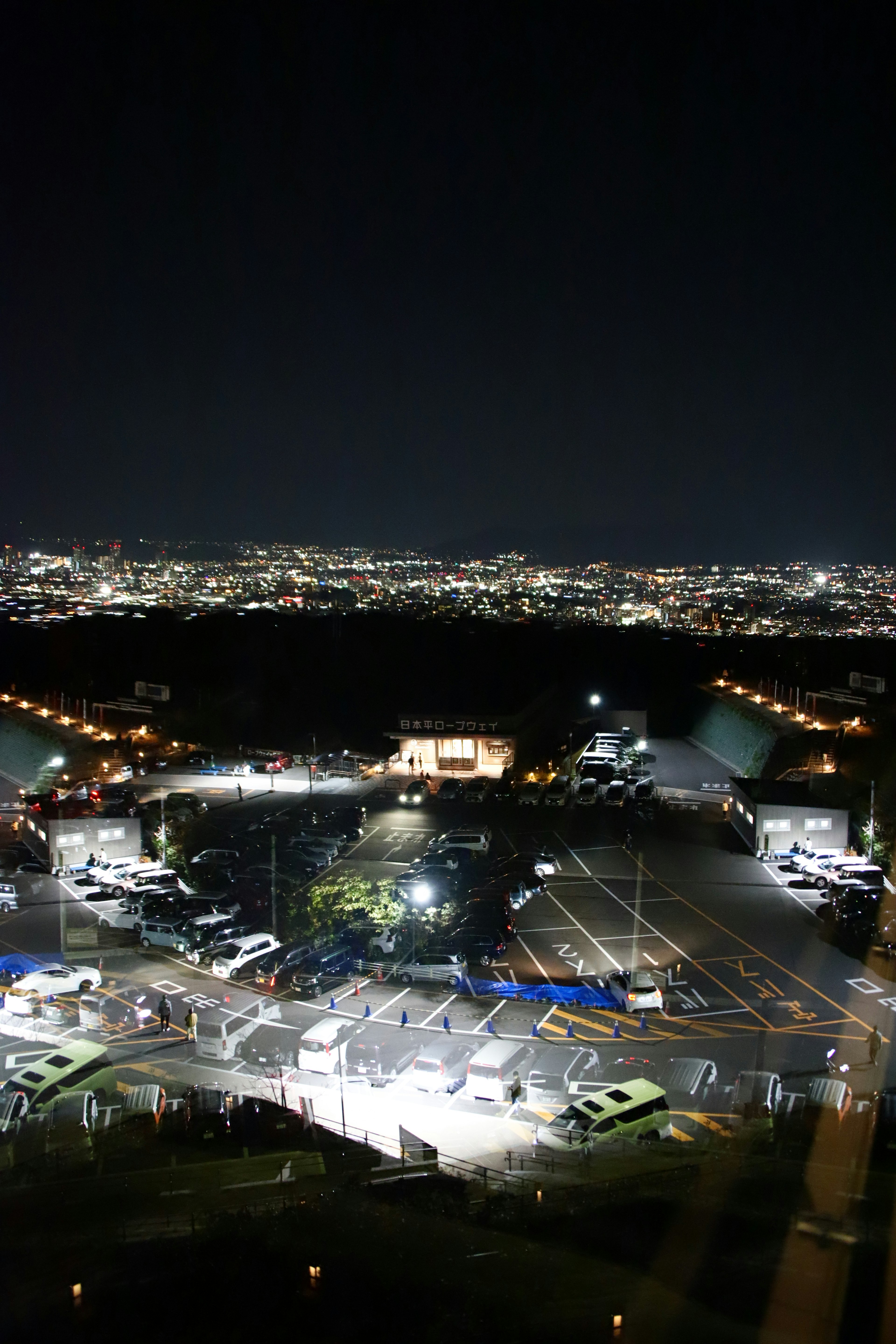 Night view of a city with a brightly lit parking area