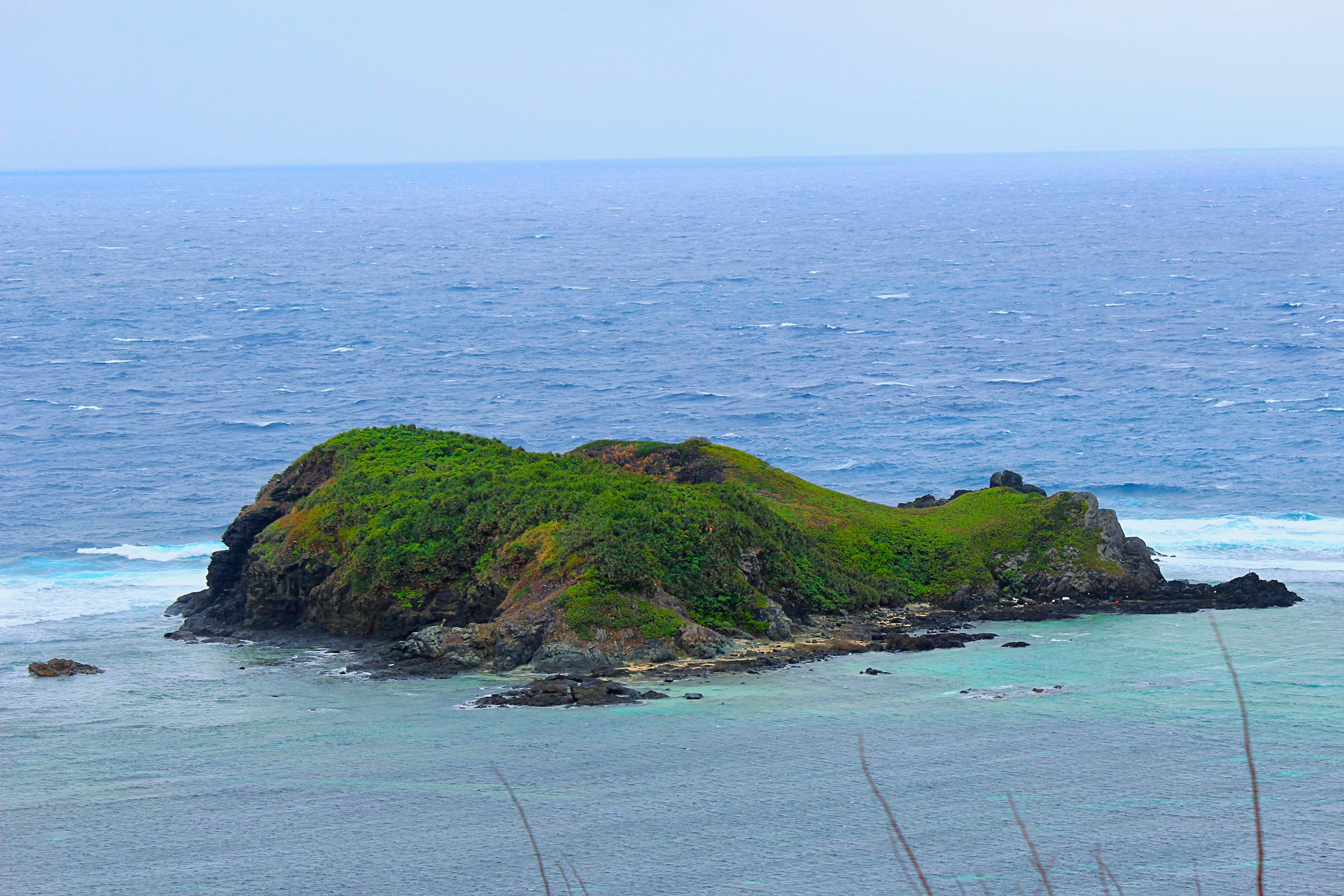 Pemandangan indah pulau kecil hijau yang dikelilingi lautan biru