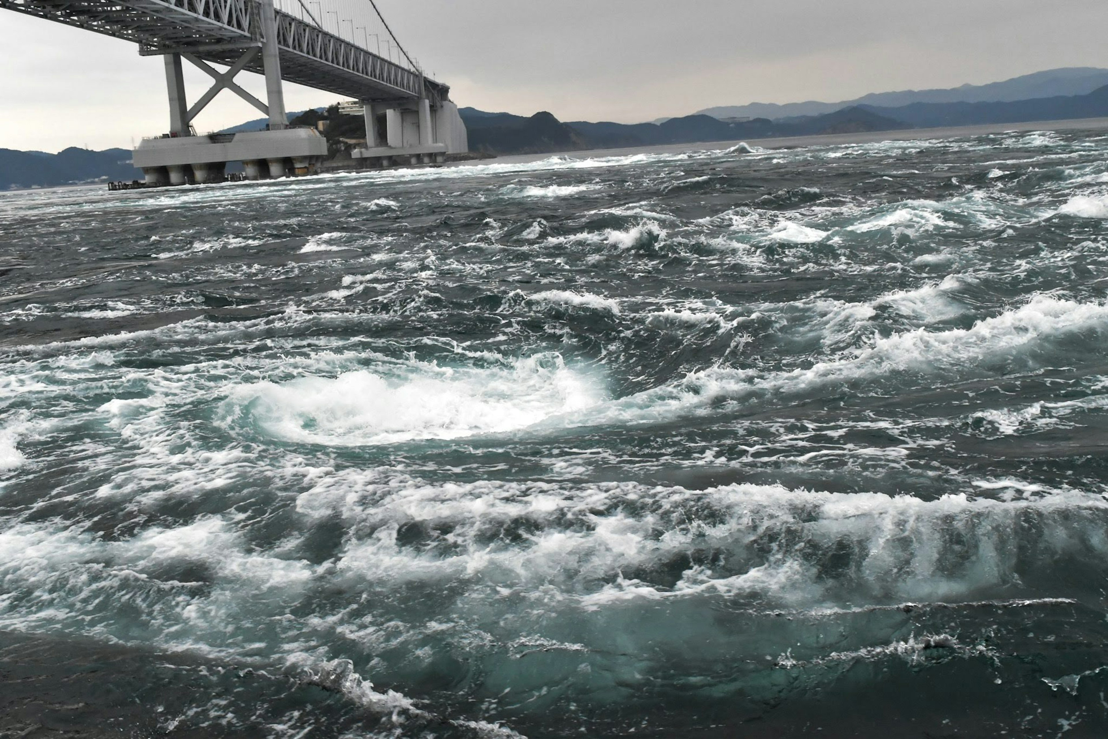 Swirling ocean currents under a bridge