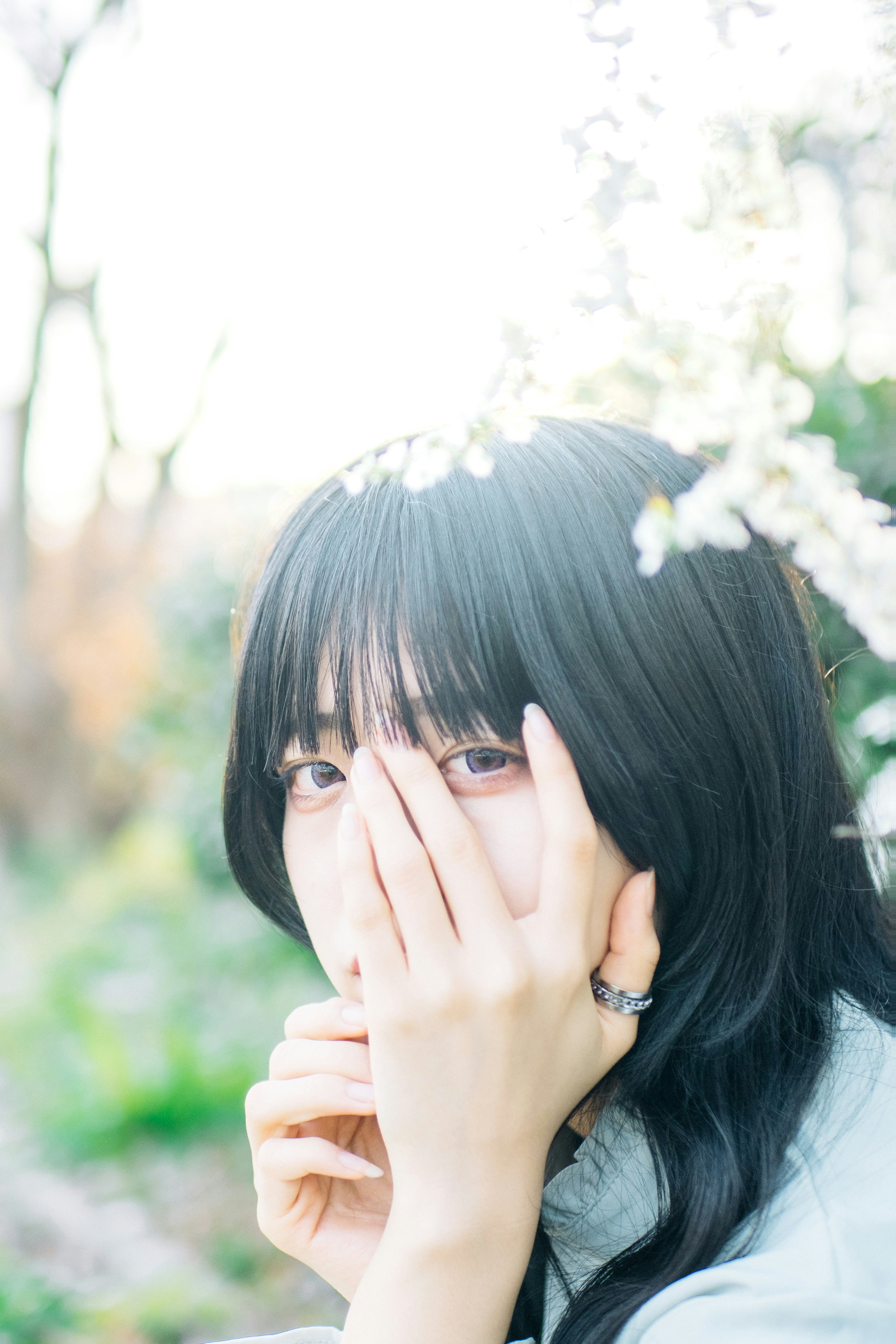 Portrait d'une femme cachant partiellement son visage avec une main parmi des fleurs