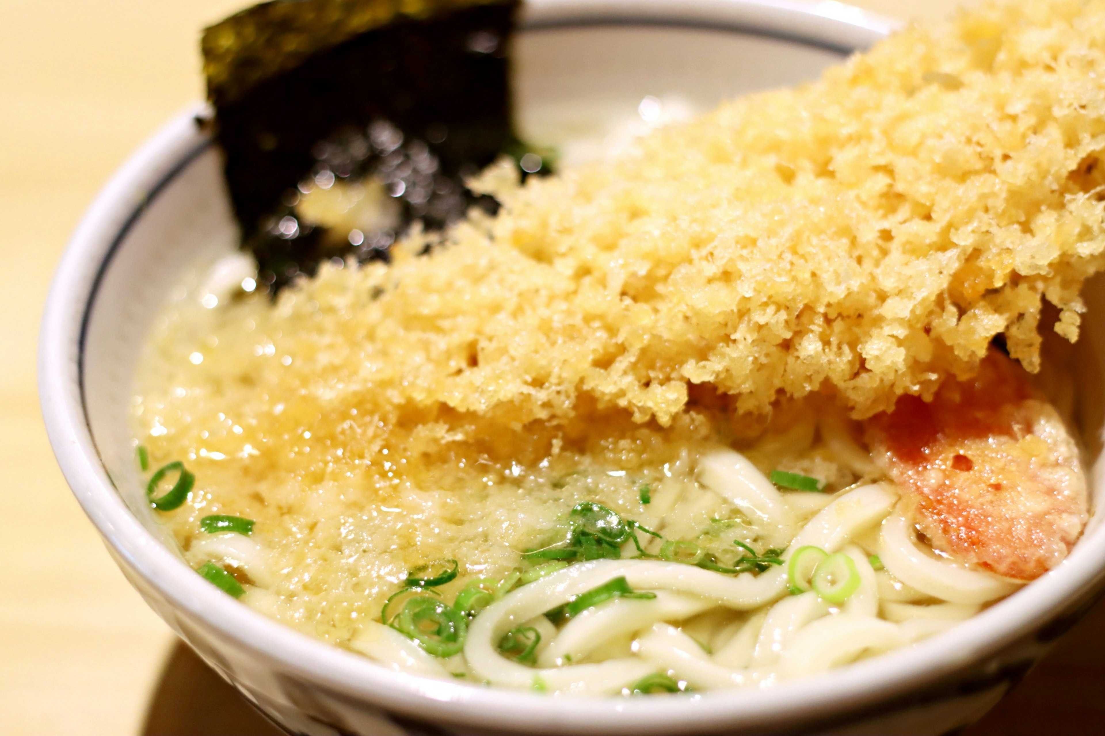 Bowl of seafood ramen topped with crispy fried elements and seaweed