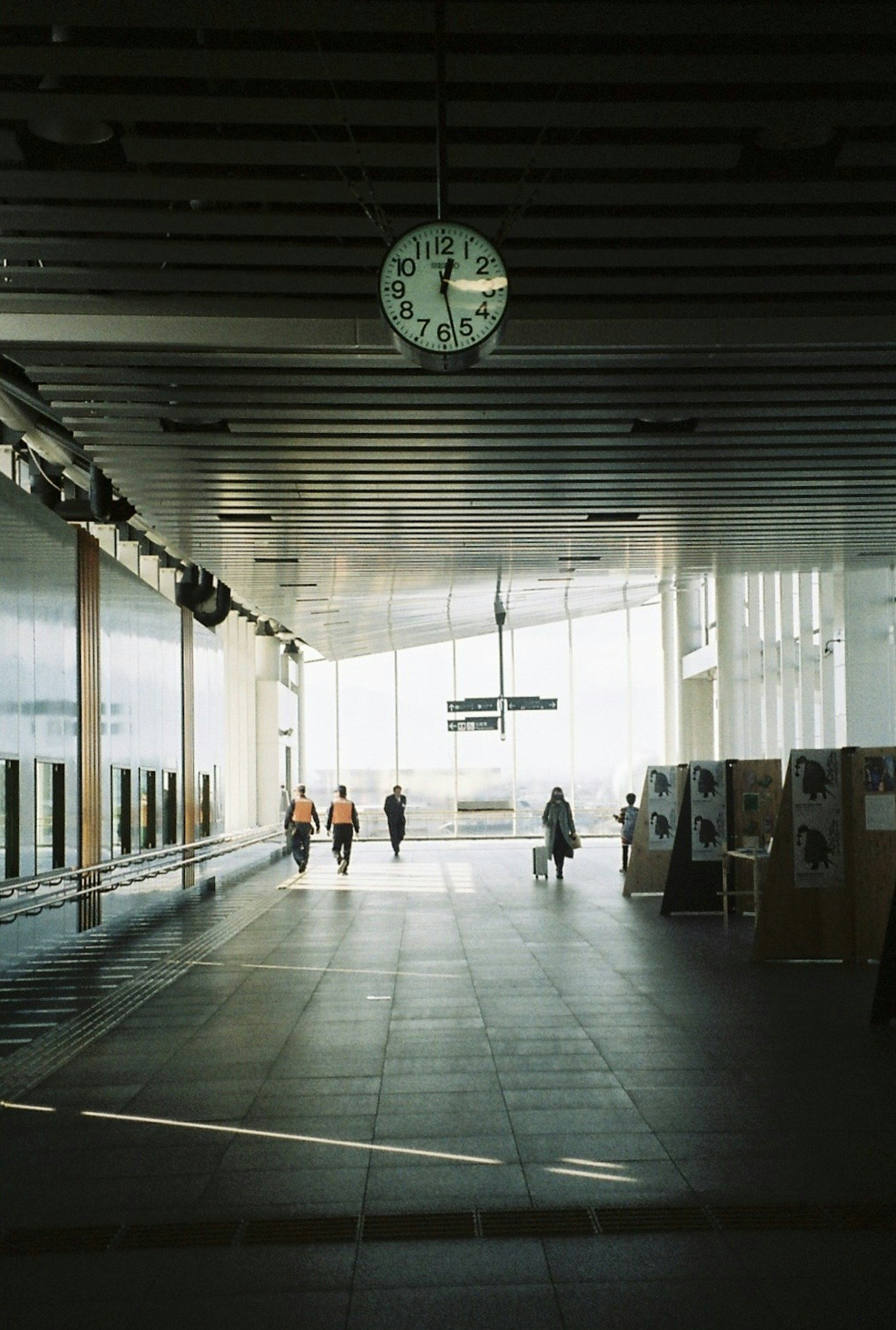 Interior modern yang cerah dengan jam dan orang-orang berjalan