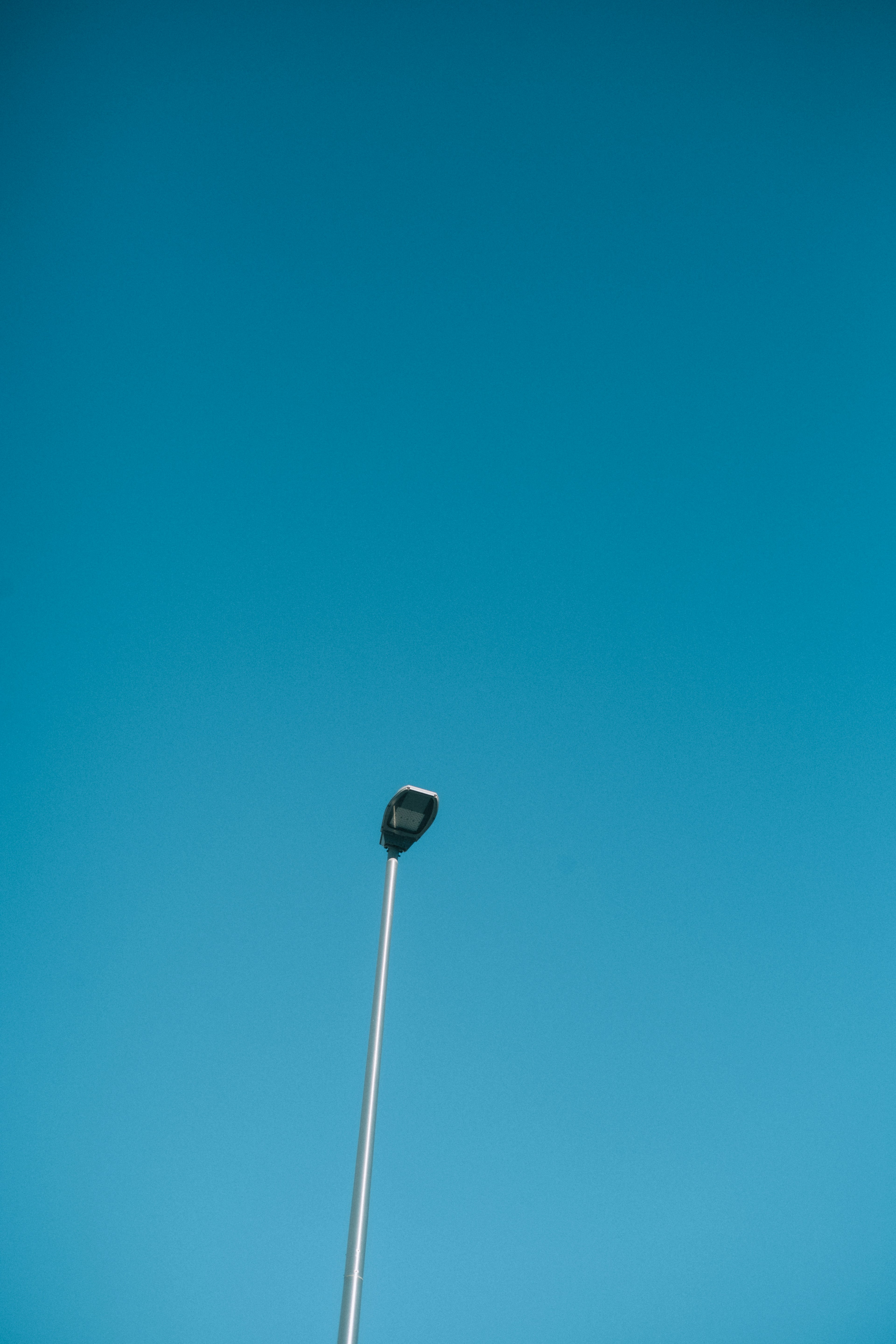 Silhouette of a street lamp against a blue sky