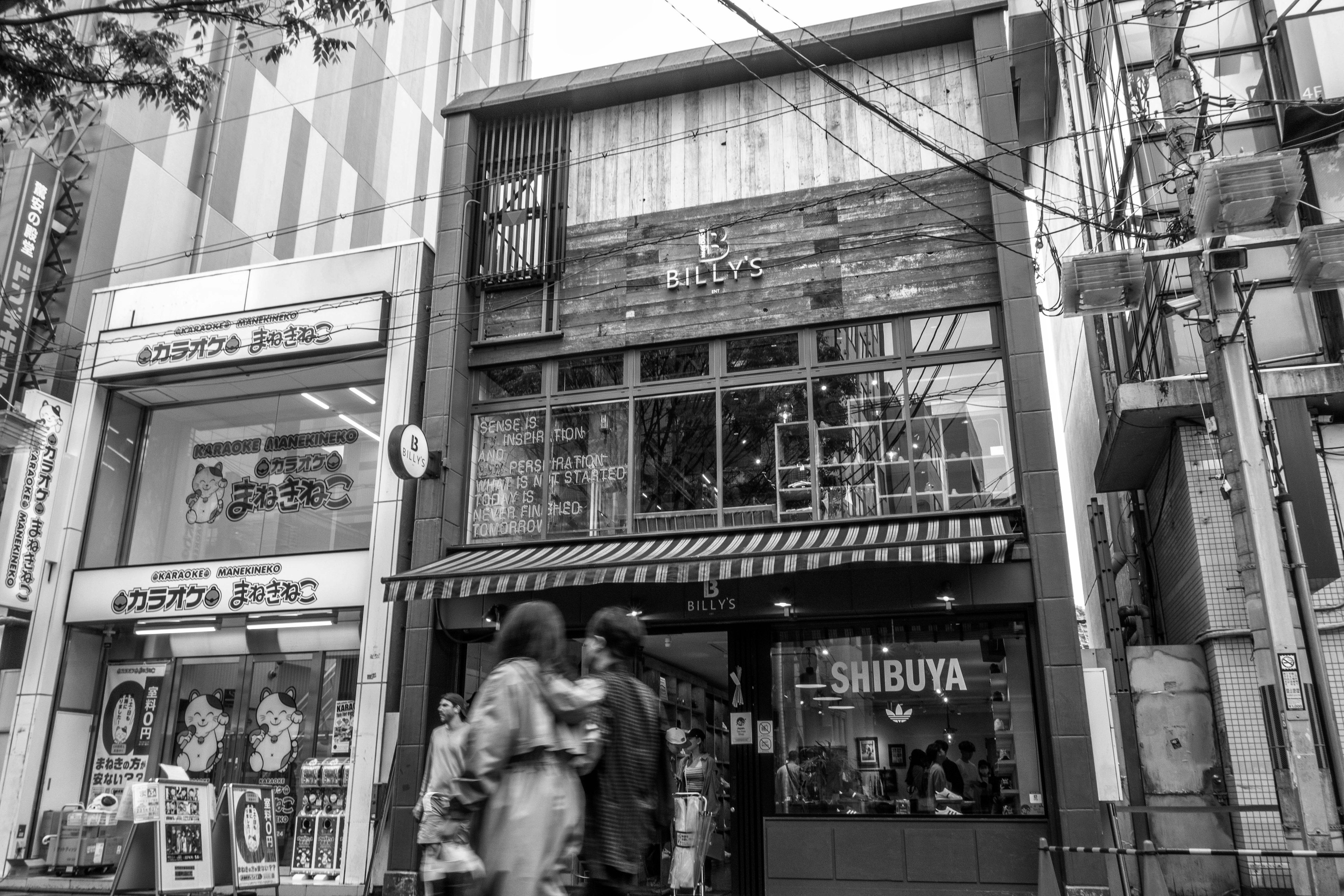 Image en noir et blanc d'une vitrine à Shibuya avec des piétons