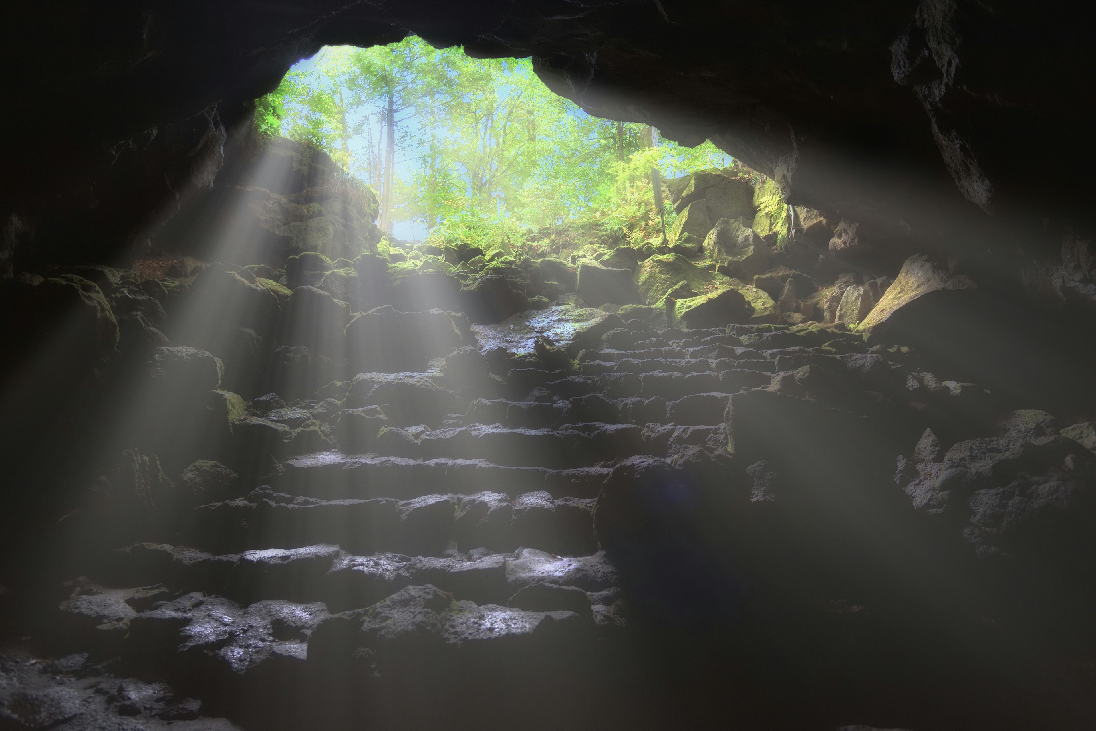 Light beams shining through a cave entrance with stone steps