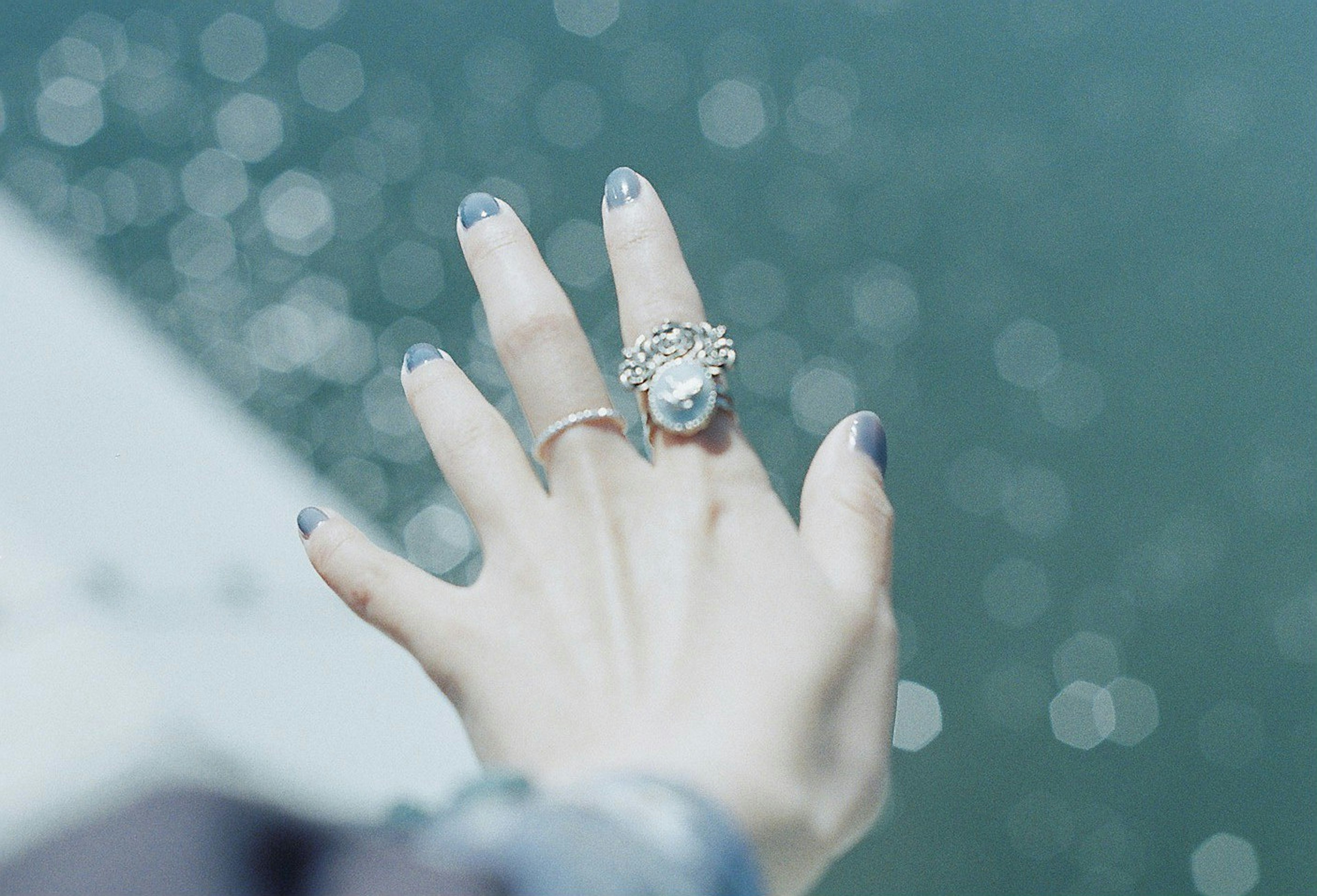 Hand with decorative rings against a shimmering water background