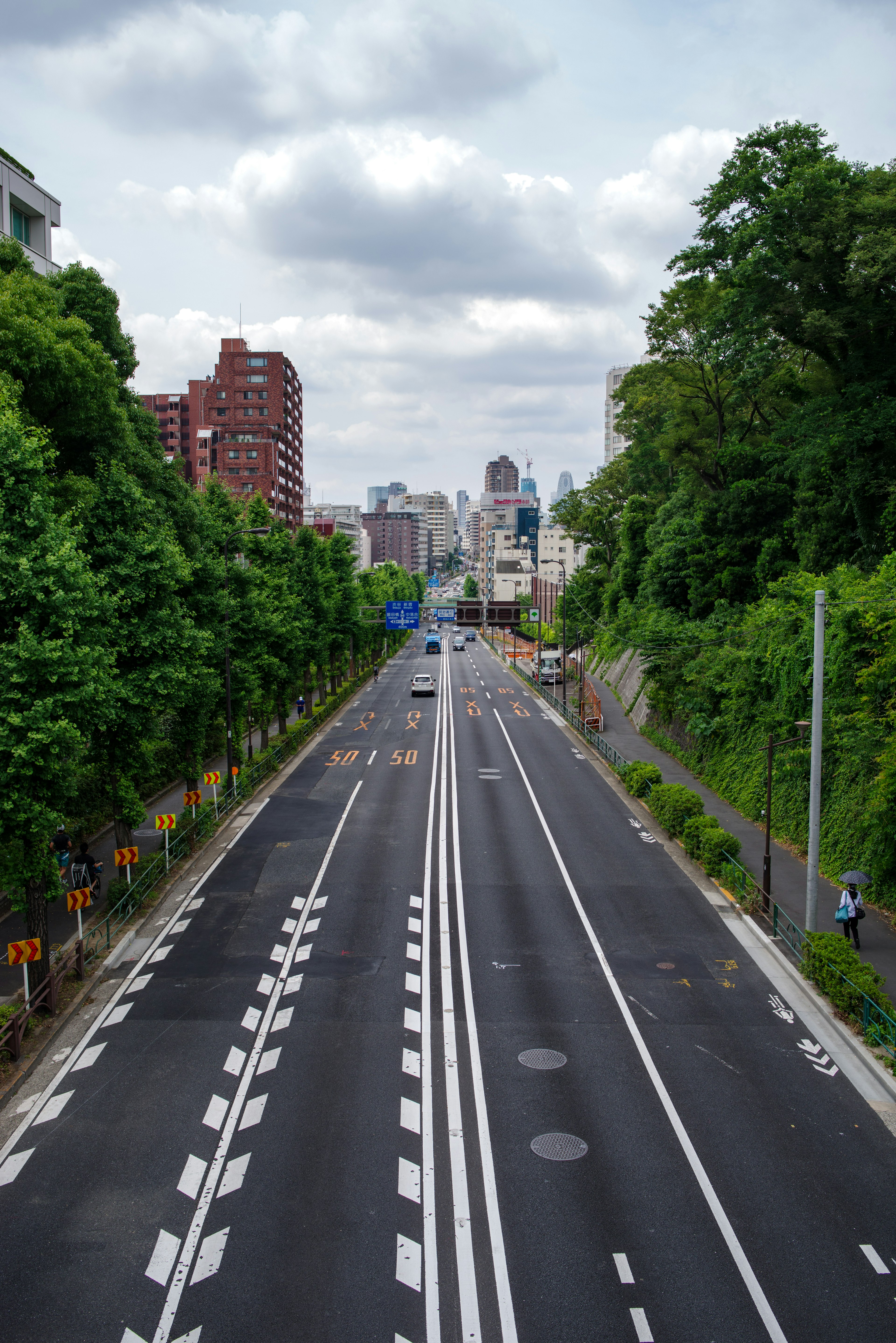 Strada urbana circondata da verde con lo skyline della città sullo sfondo