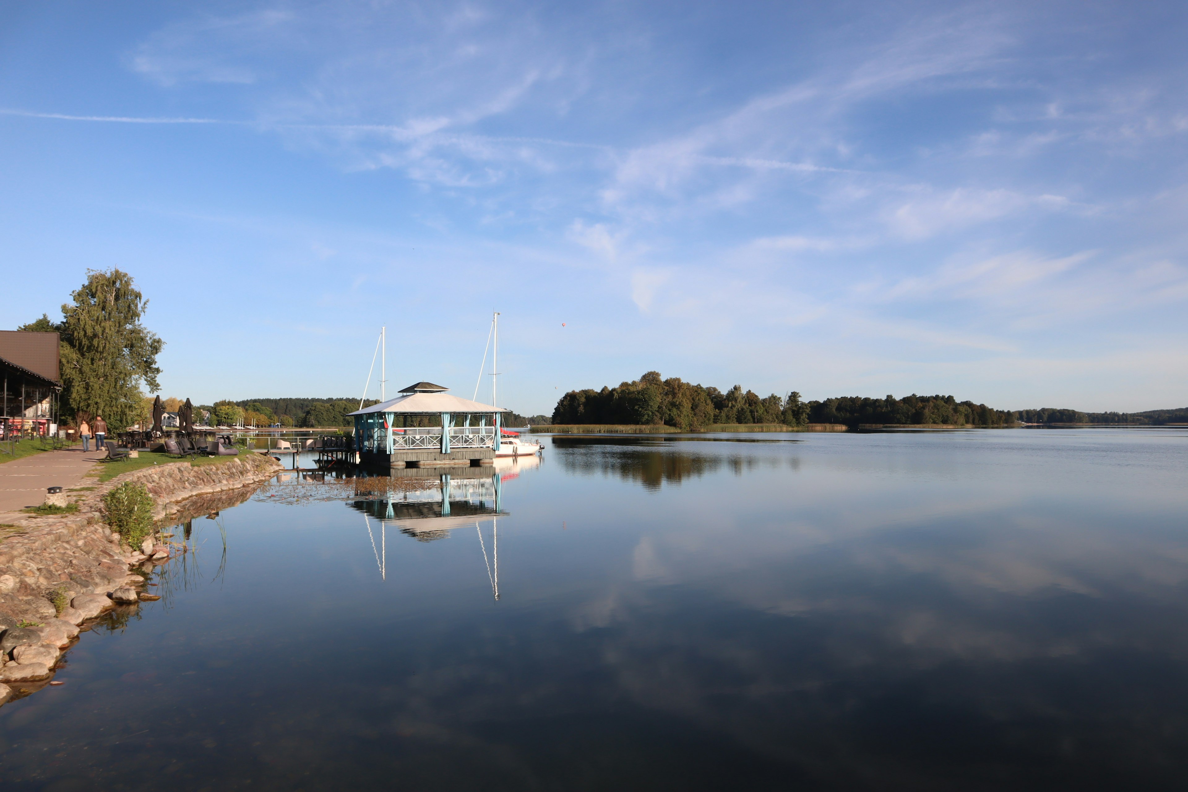 Vue tranquille du lac avec un bateau ciel bleu et nuages blancs réfléchis