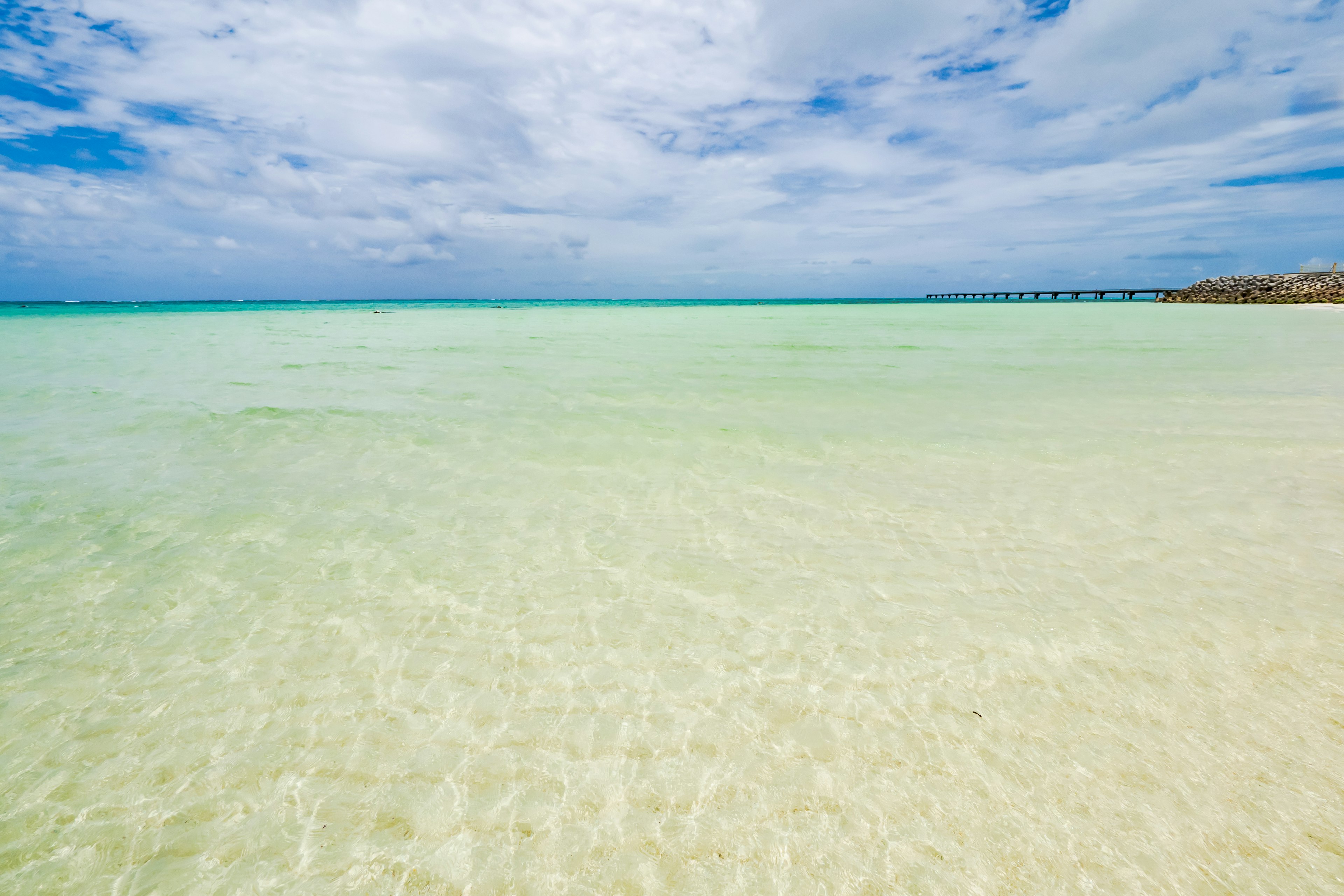 Pemandangan pantai dengan air jernih dan langit biru