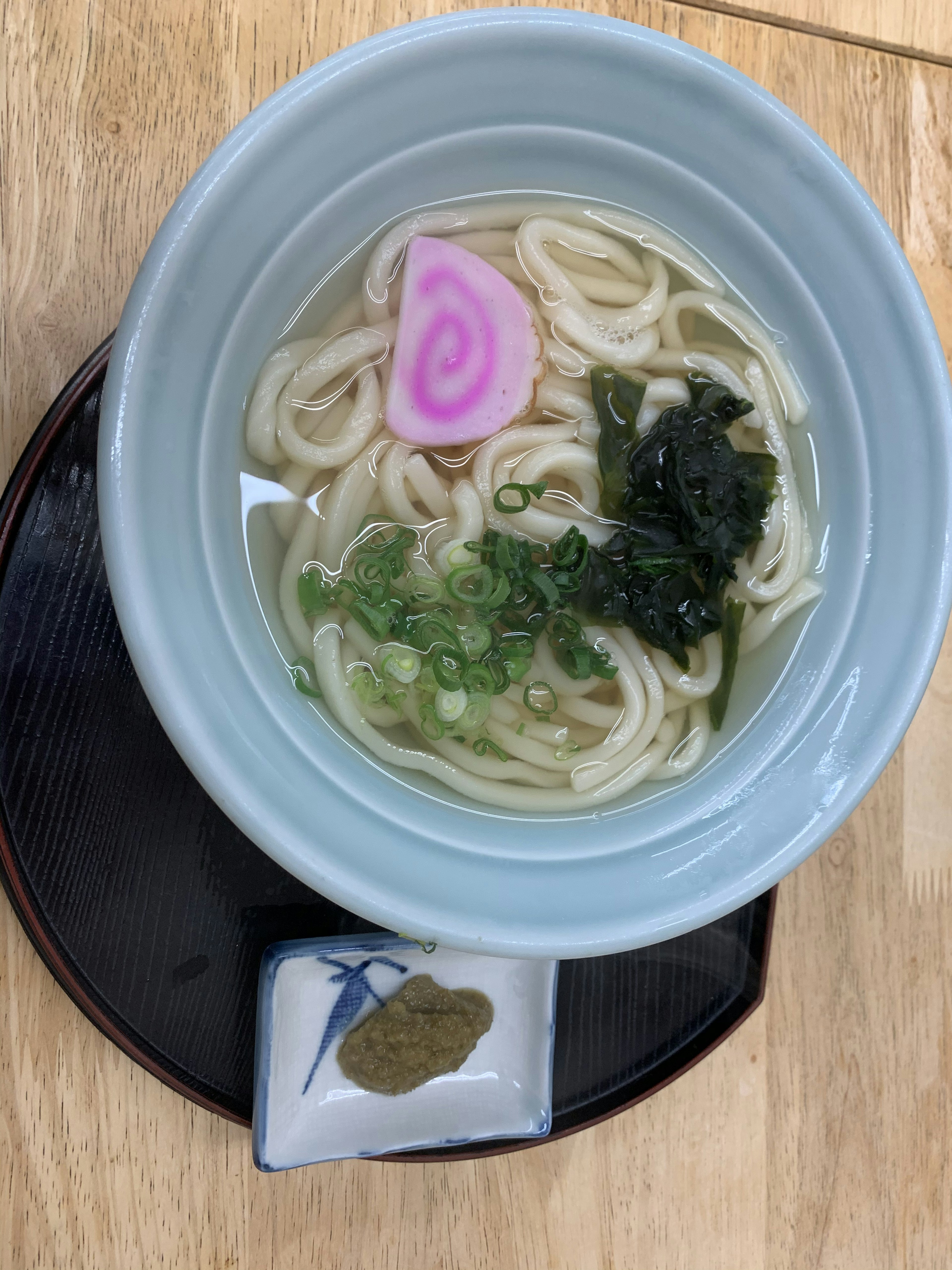 青い器に盛られたうどんとネギのスープ