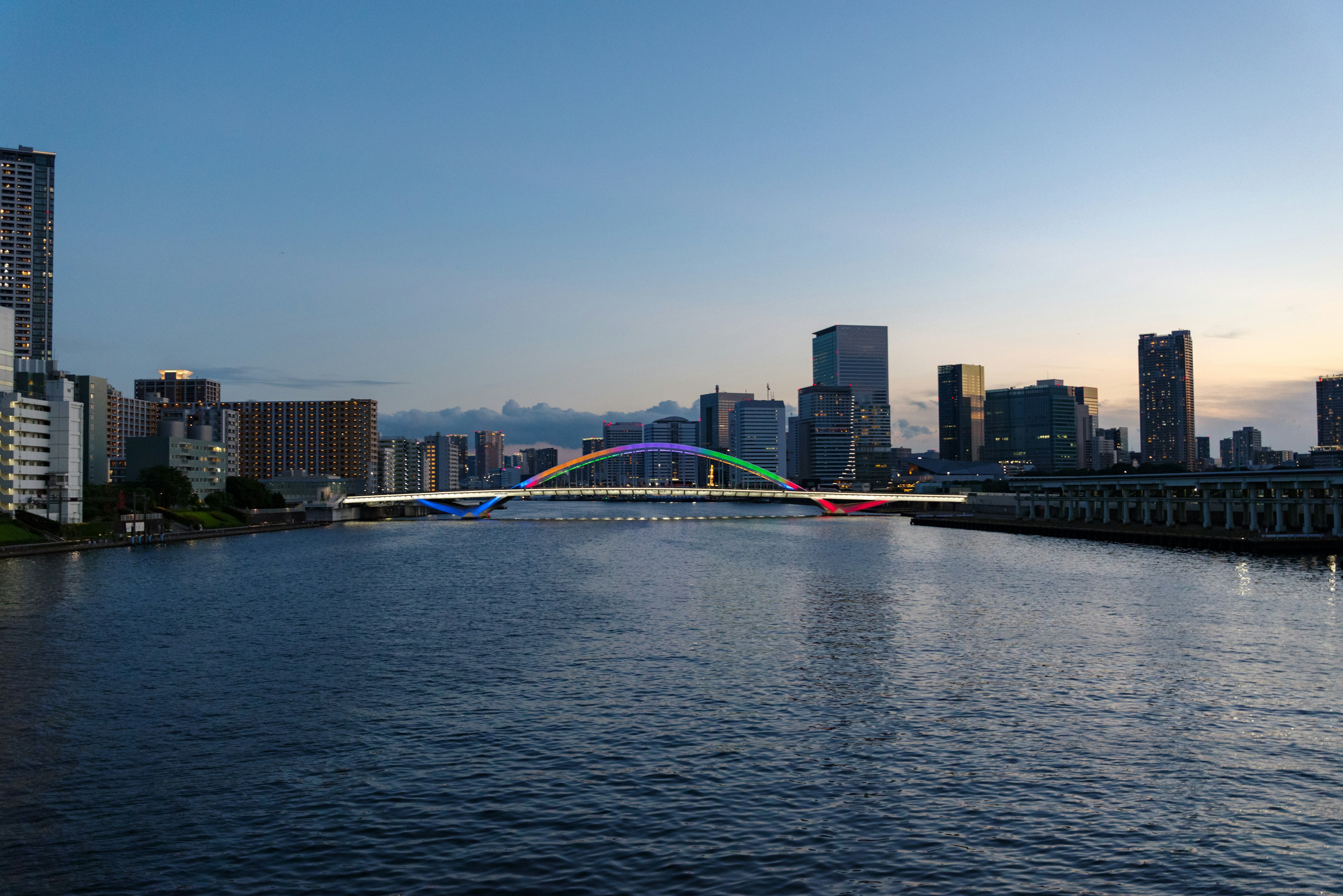 Horizonte de la ciudad al anochecer con un puente colorido sobre el río