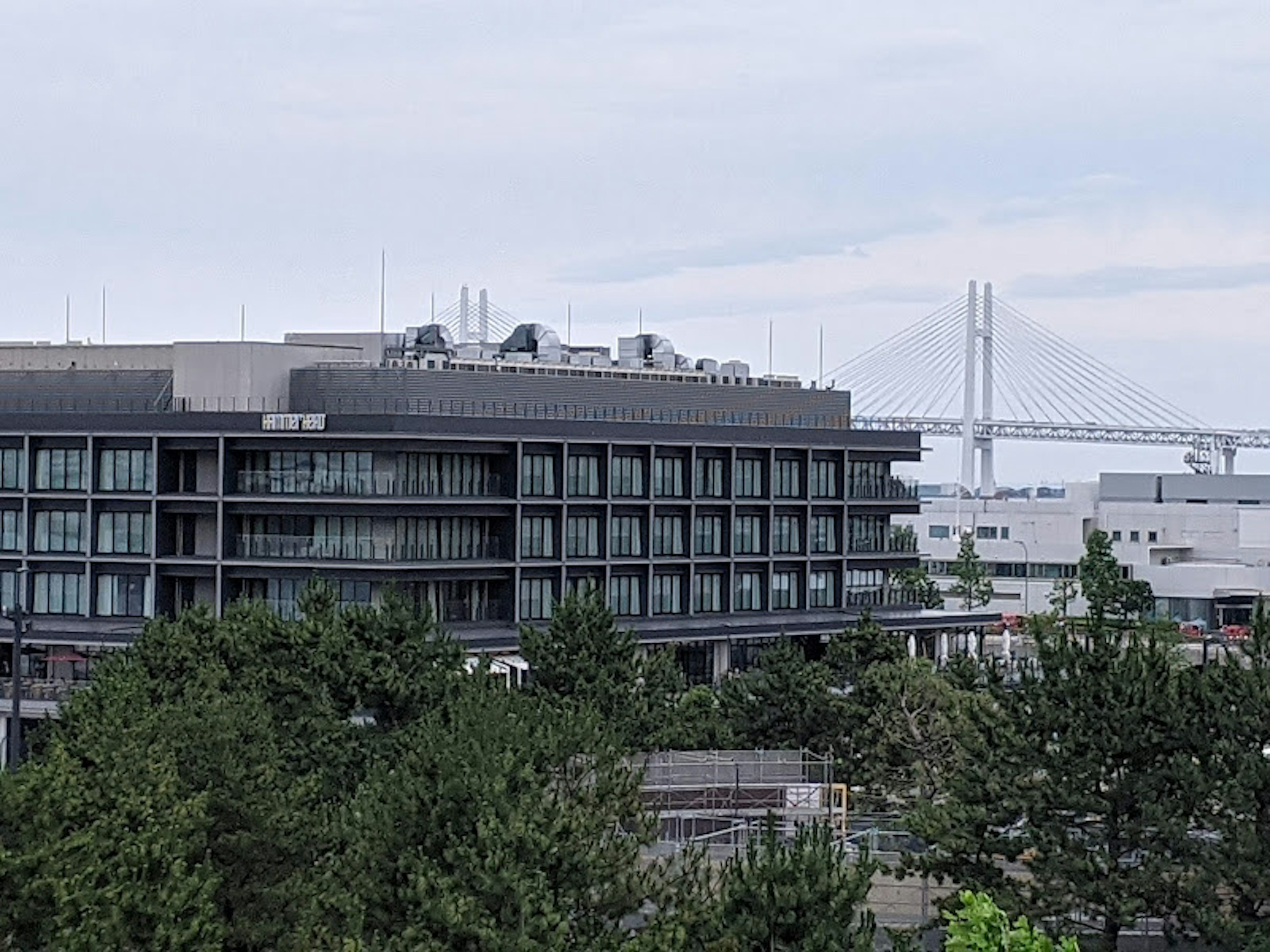 Modern building with lush greenery and a distant bridge in the background