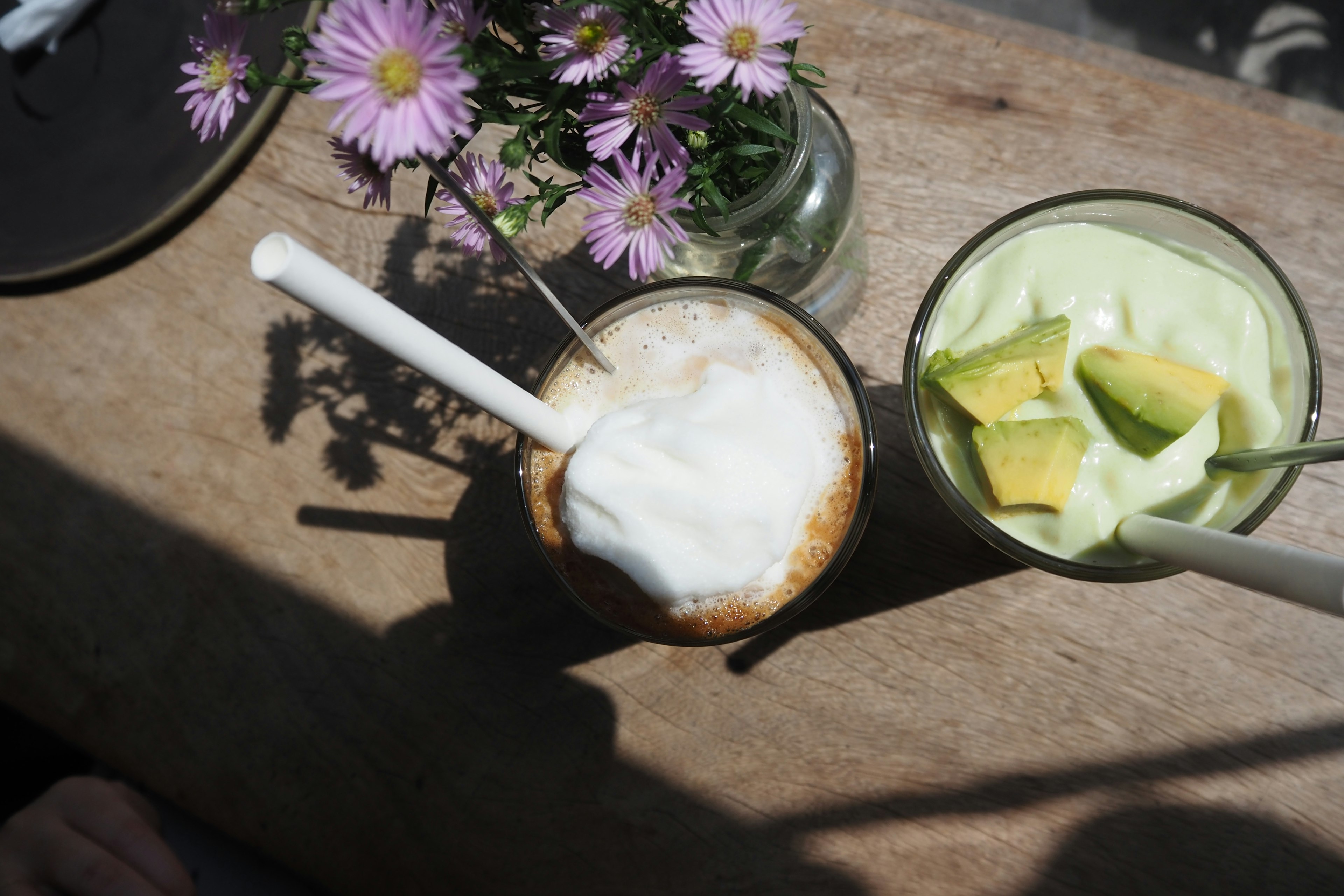 A photo of a café latte and a green dessert on a table with flowers