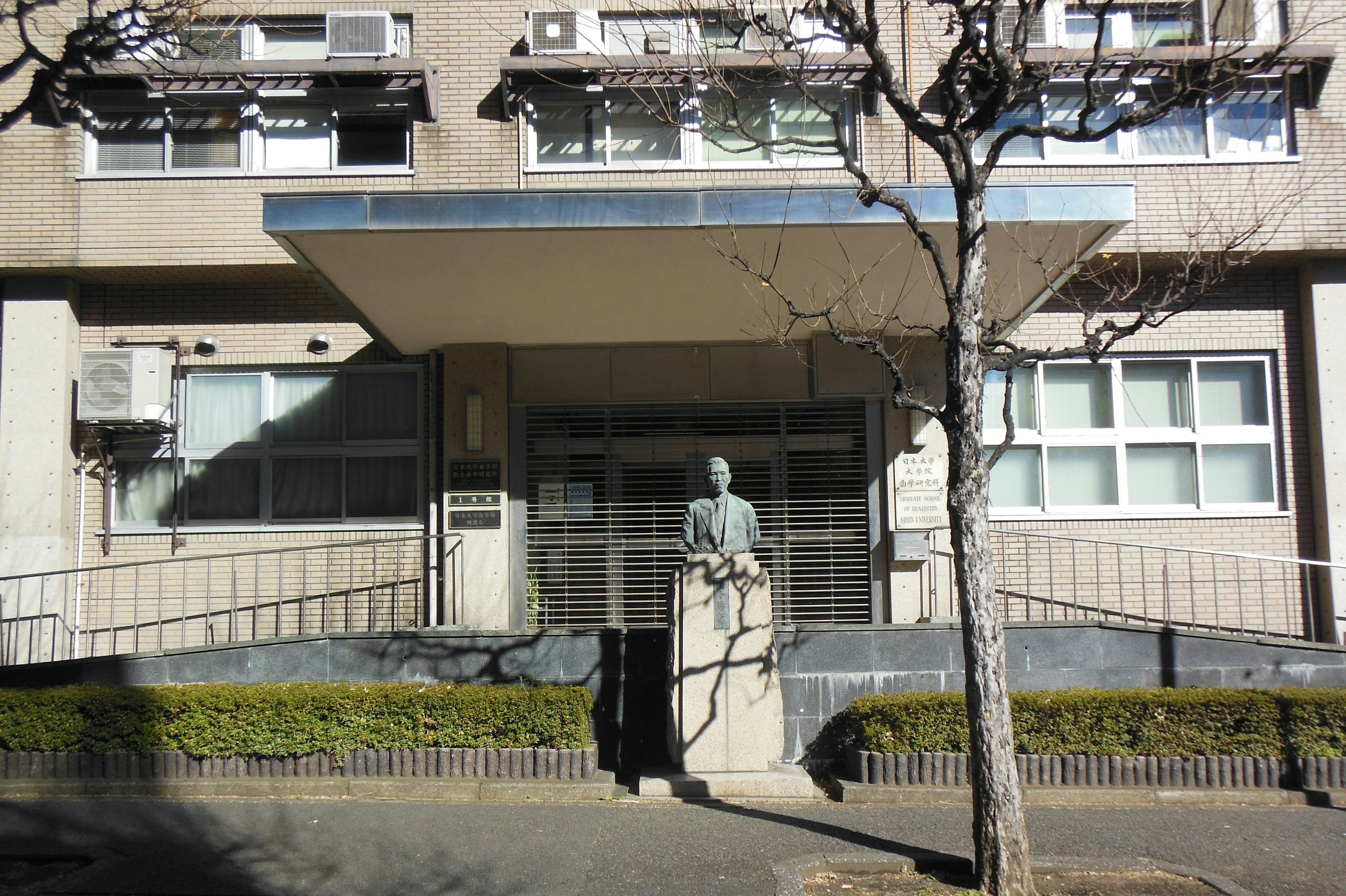 Statue vor einem Gebäude mit grünen Büschen und Bäumen