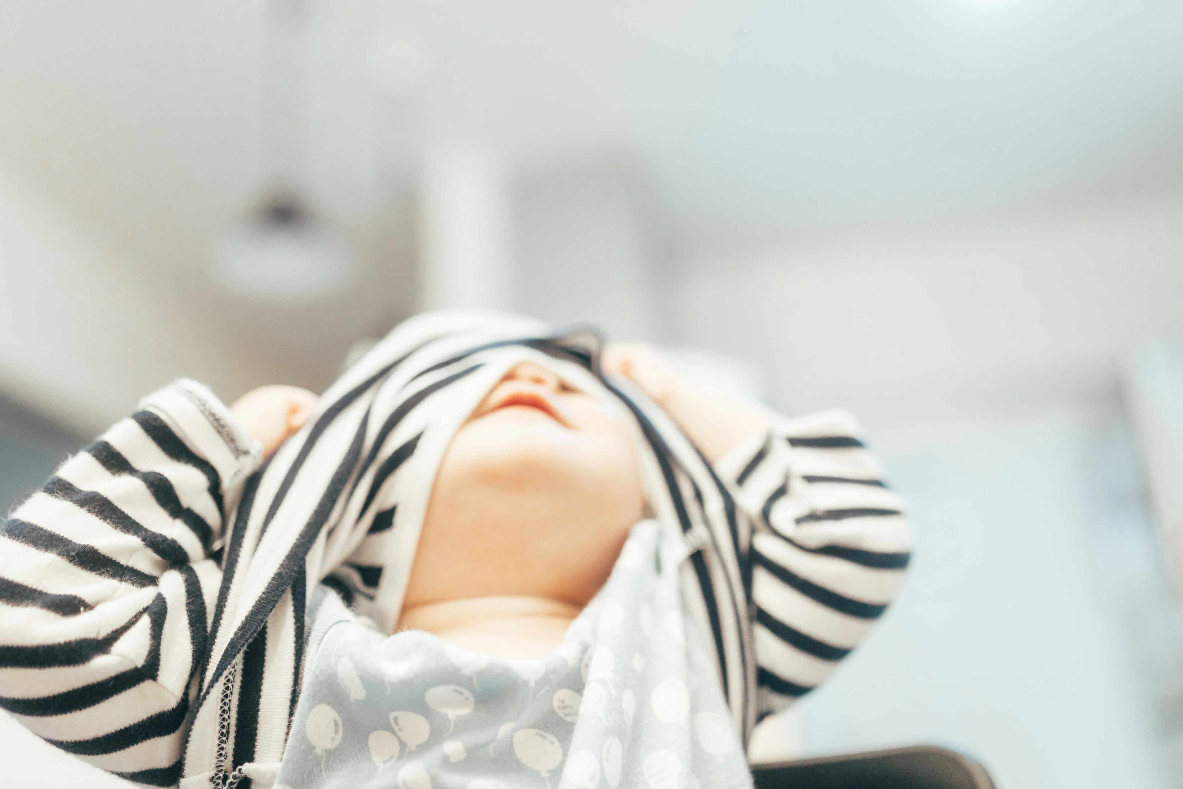 Bébé tirant joyeusement un t-shirt rayé sur sa tête et souriant