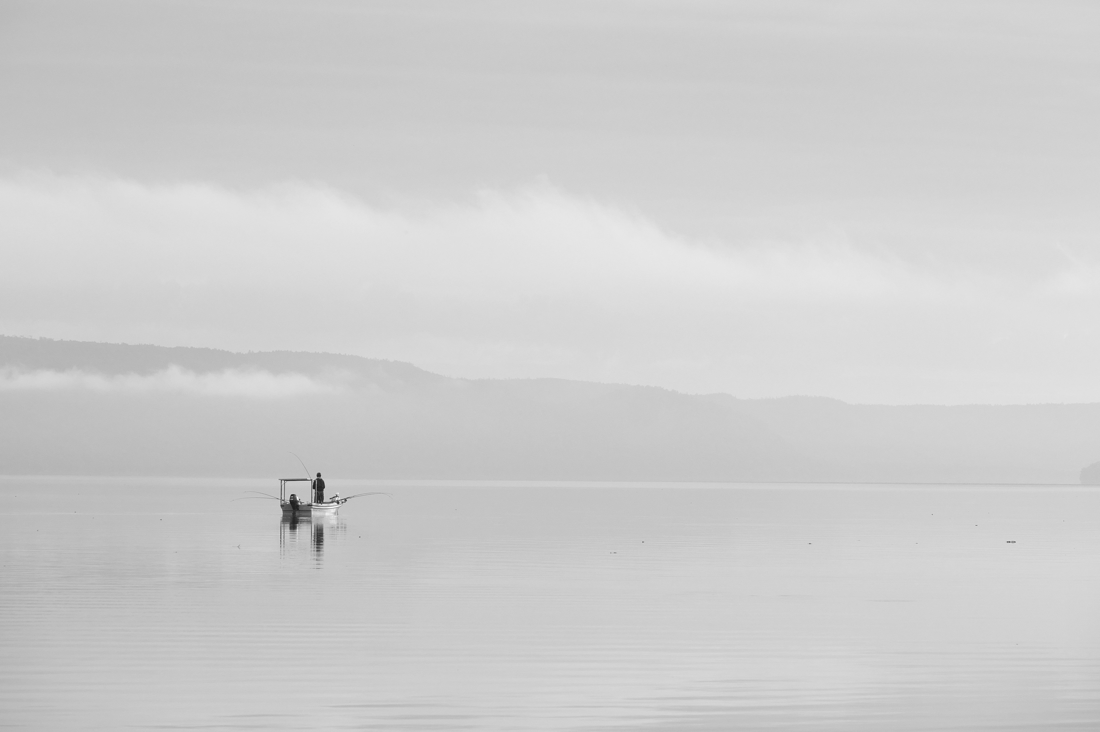 ภาพเงียบสงบขาวดำของคนพายเรือเล็กในทะเลสาบ