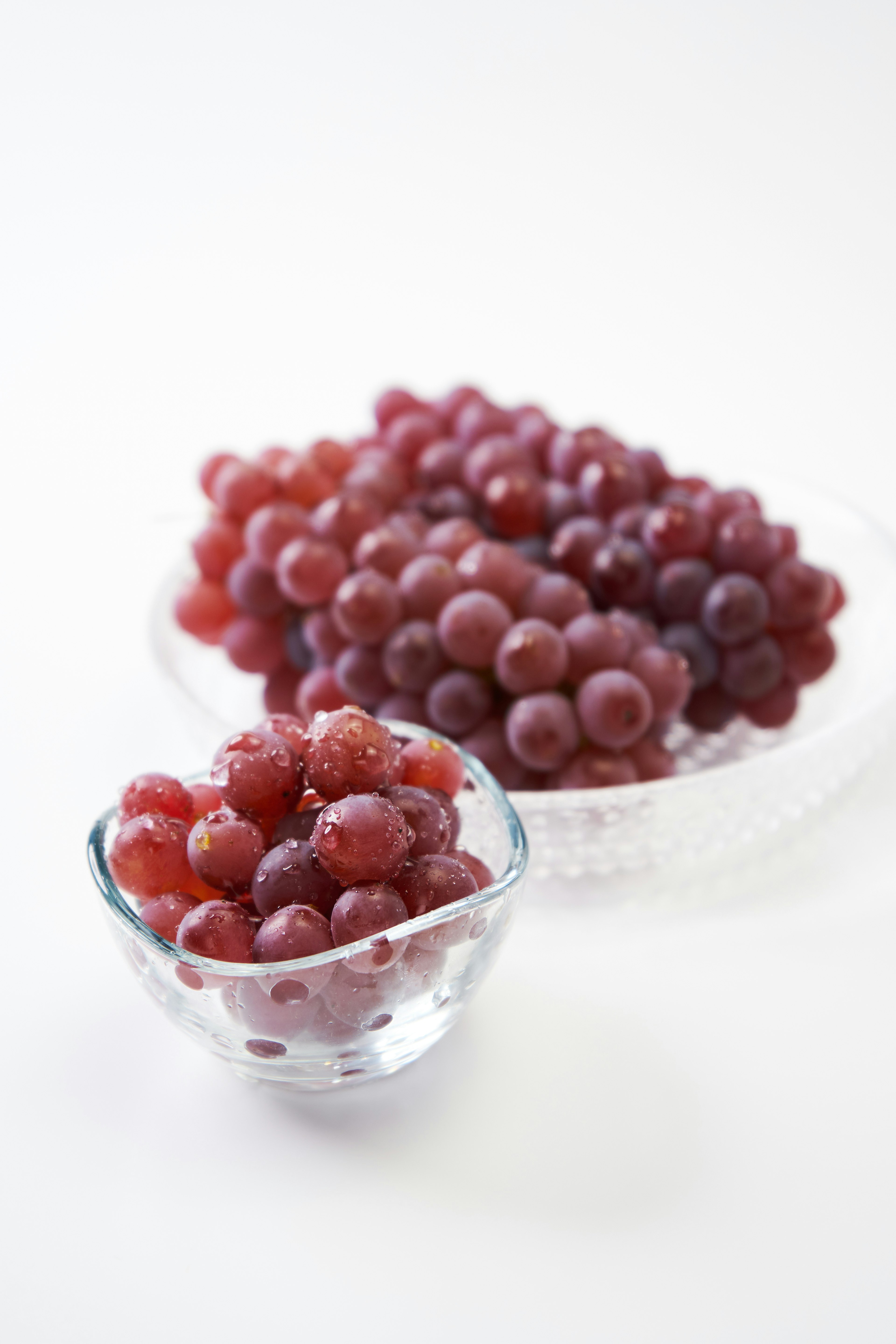 Red grapes arranged in a large bowl and a small glass bowl