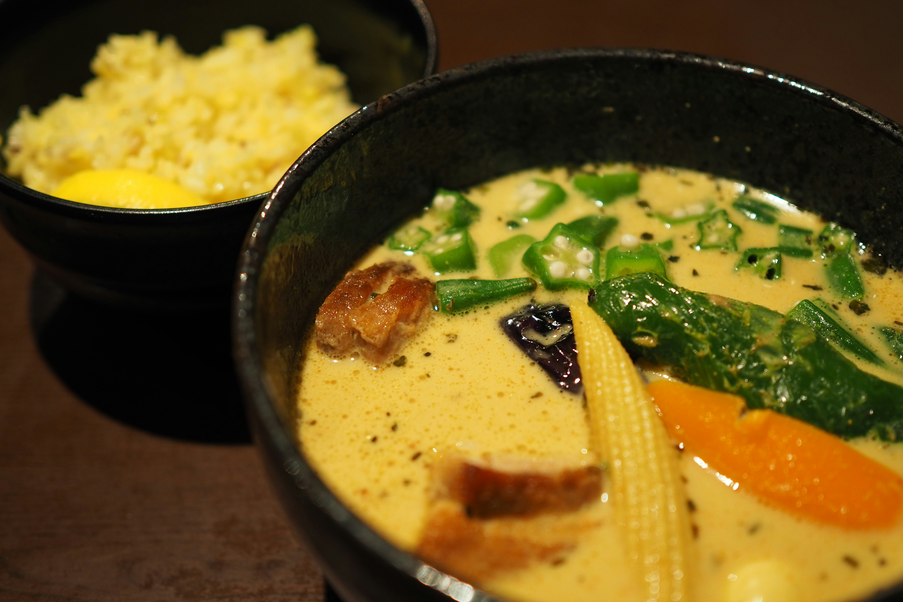 Bol de soupe crémeuse avec des légumes variés et de la viande accompagné d'un plat de riz