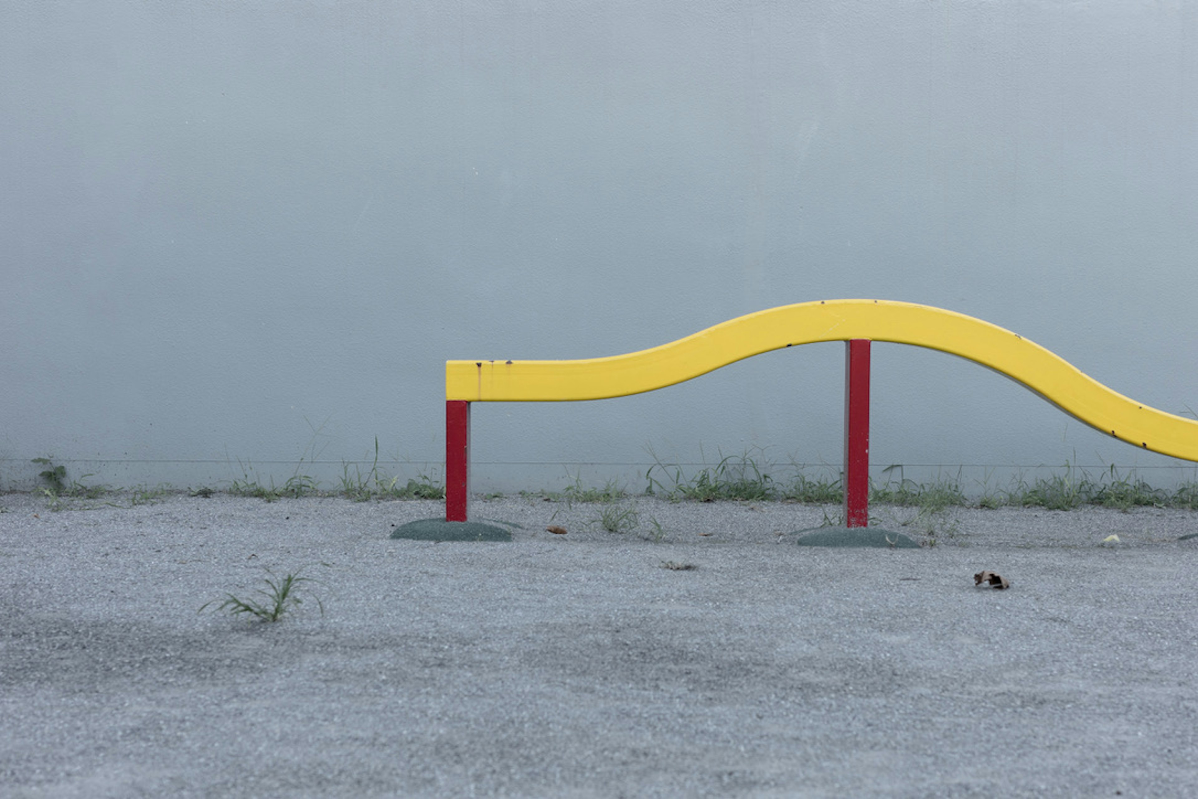 A yellow wave-shaped structure with red supports in an empty landscape