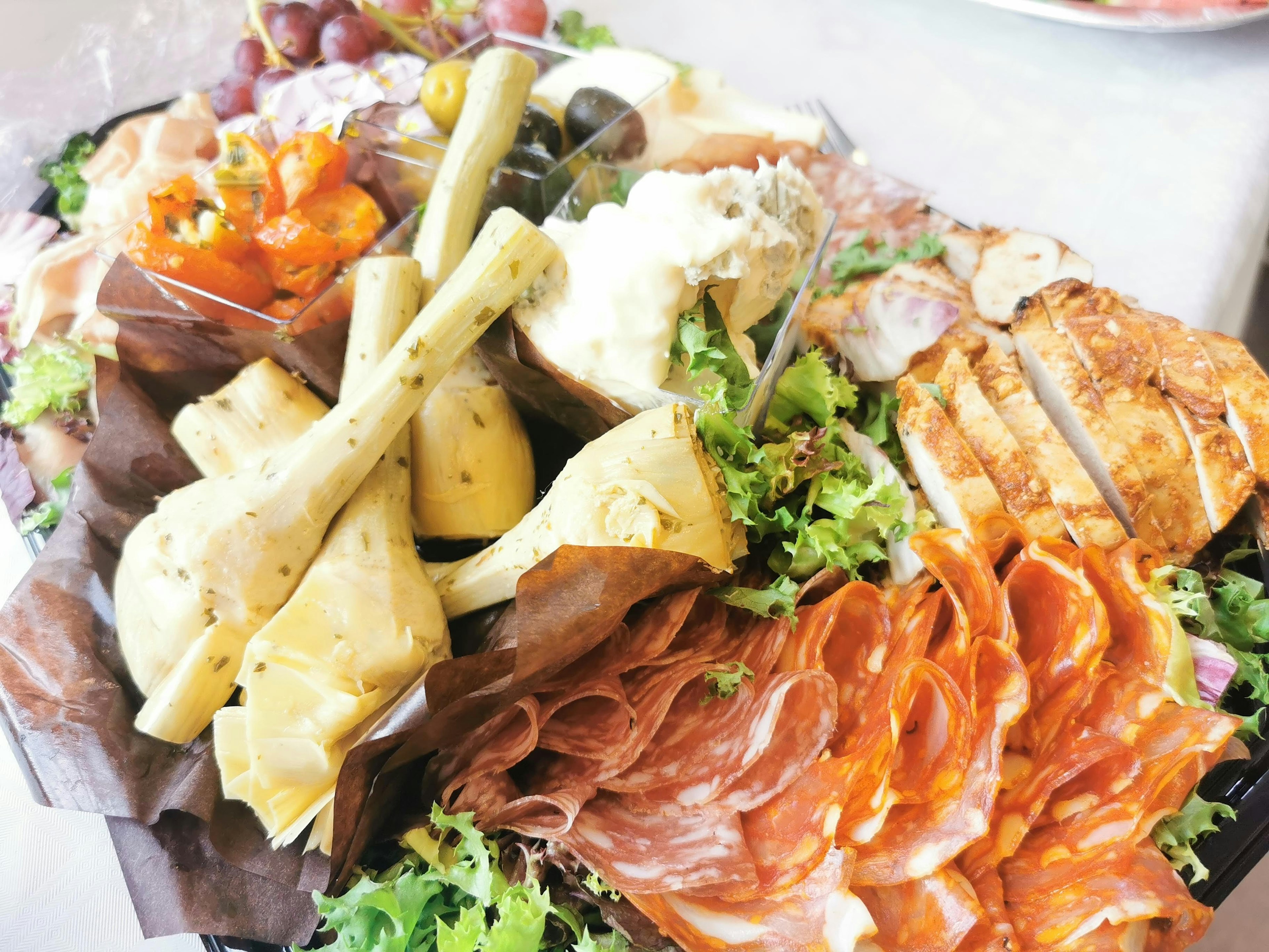 Plateau coloré de fromages et de viandes garni de laitue fraîche et de fruits