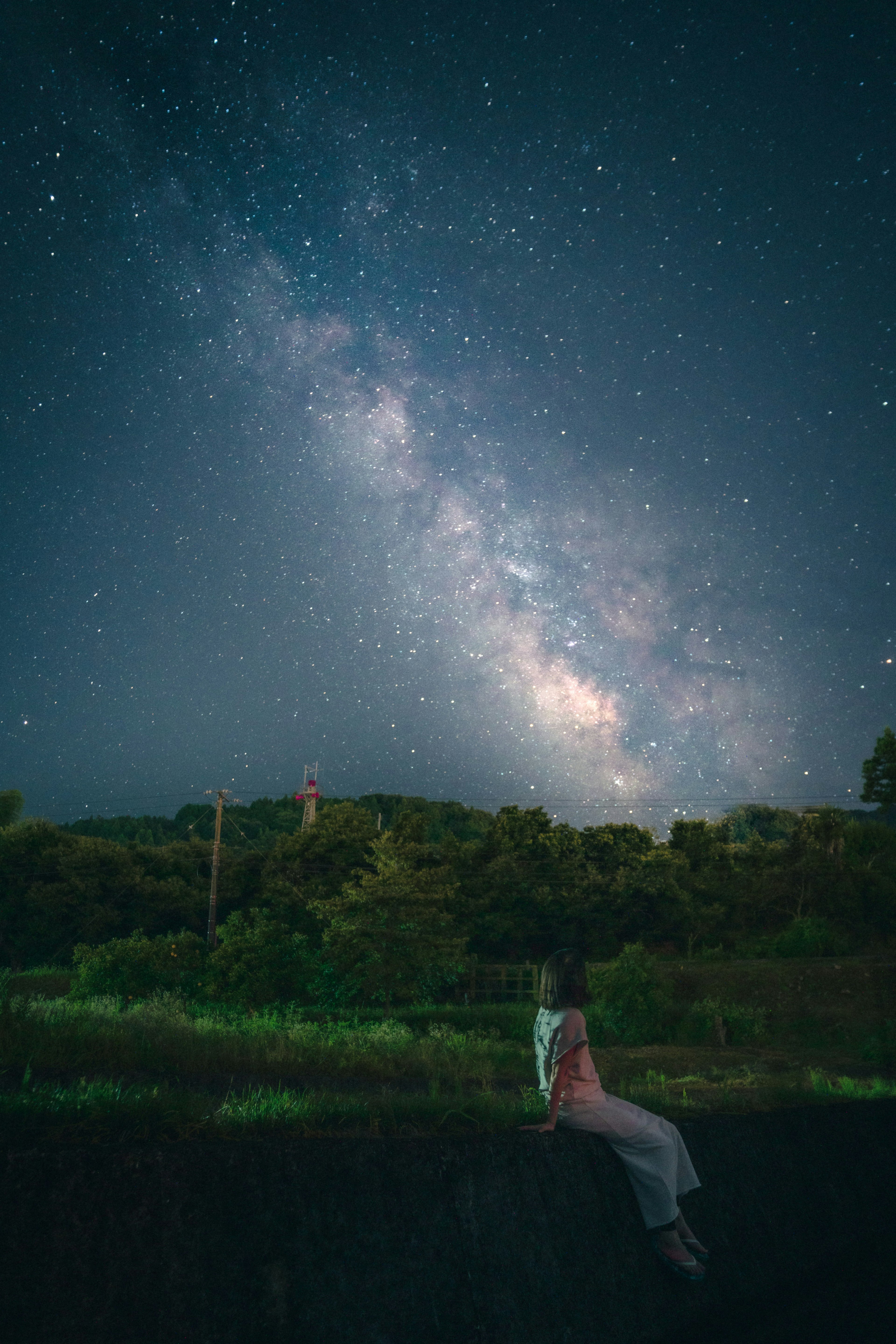 星空の下で座っている女性と天の川の美しい景色