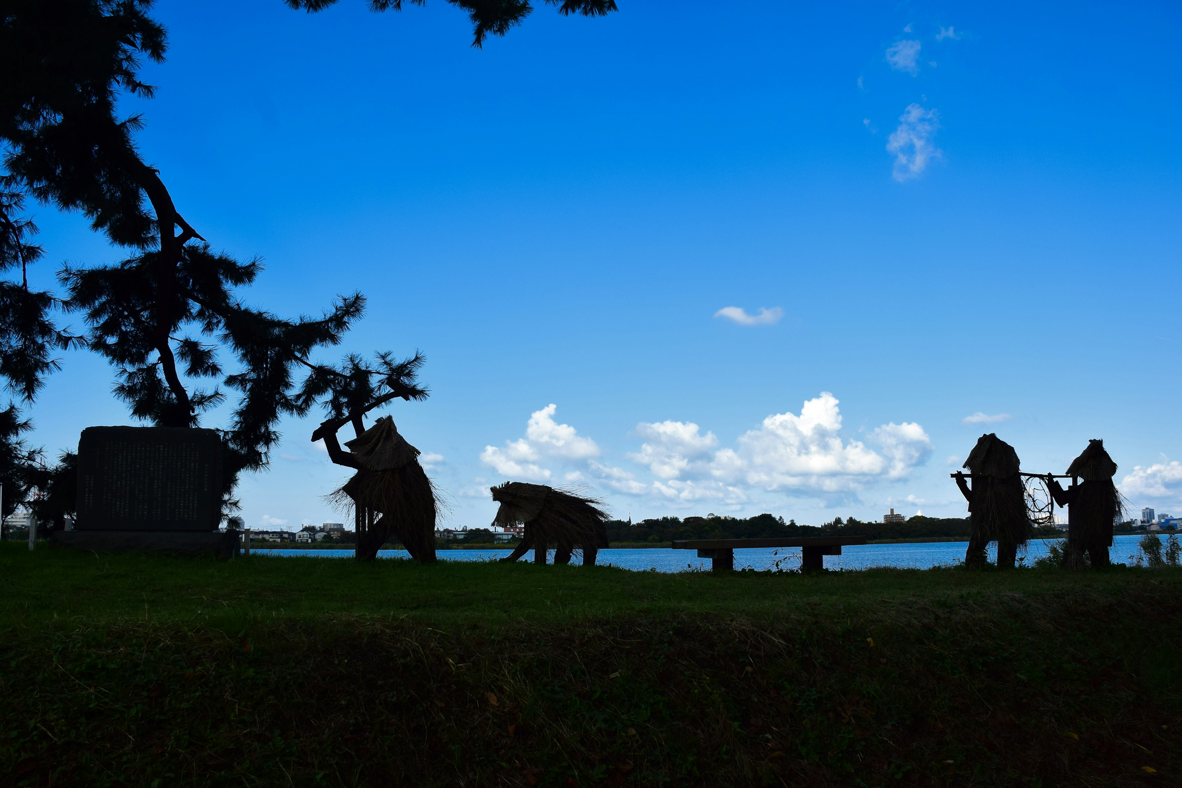 Silhouetted figures of people and animals against a blue sky