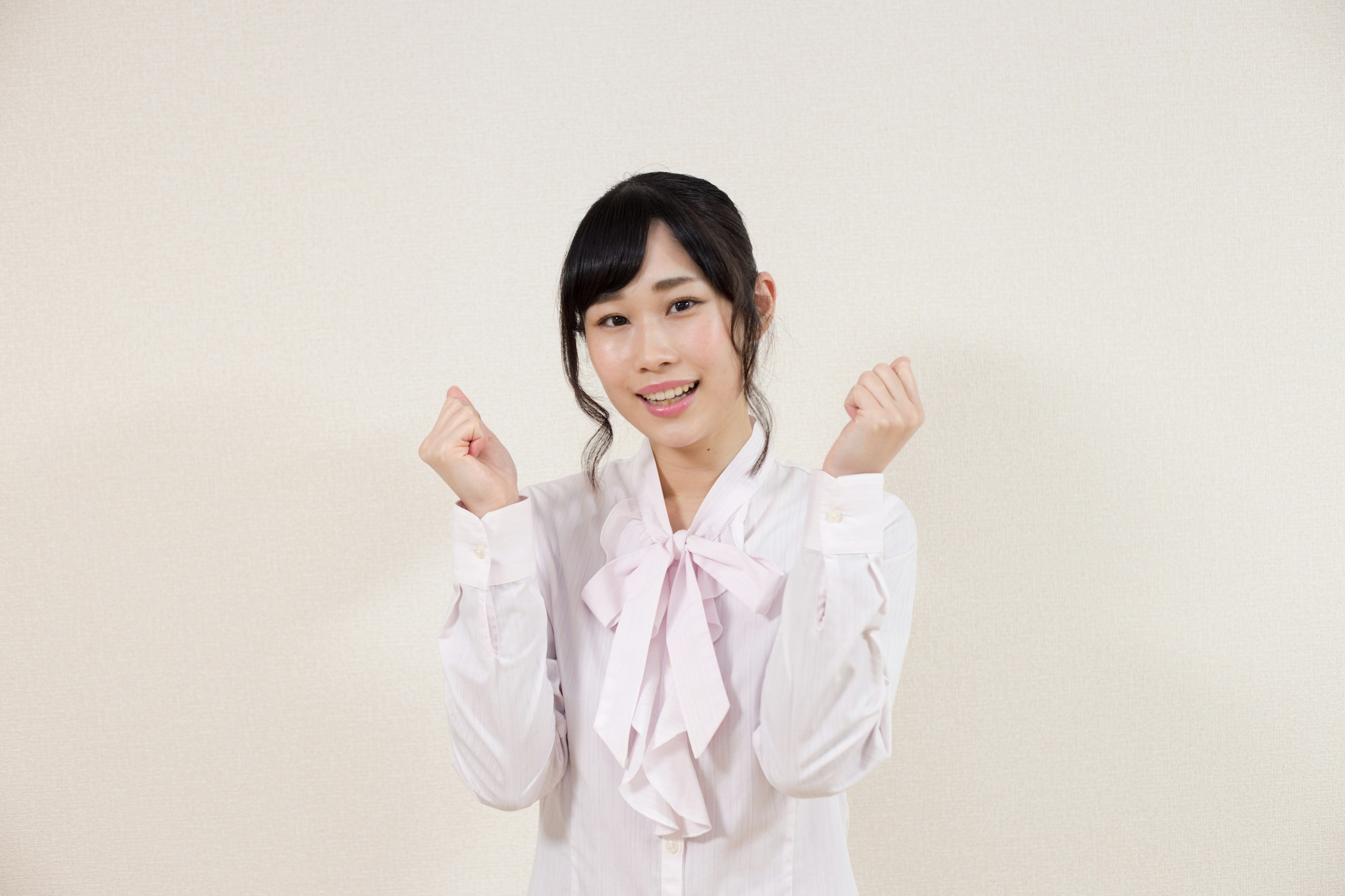 Woman smiling and raising her hands wearing a white shirt