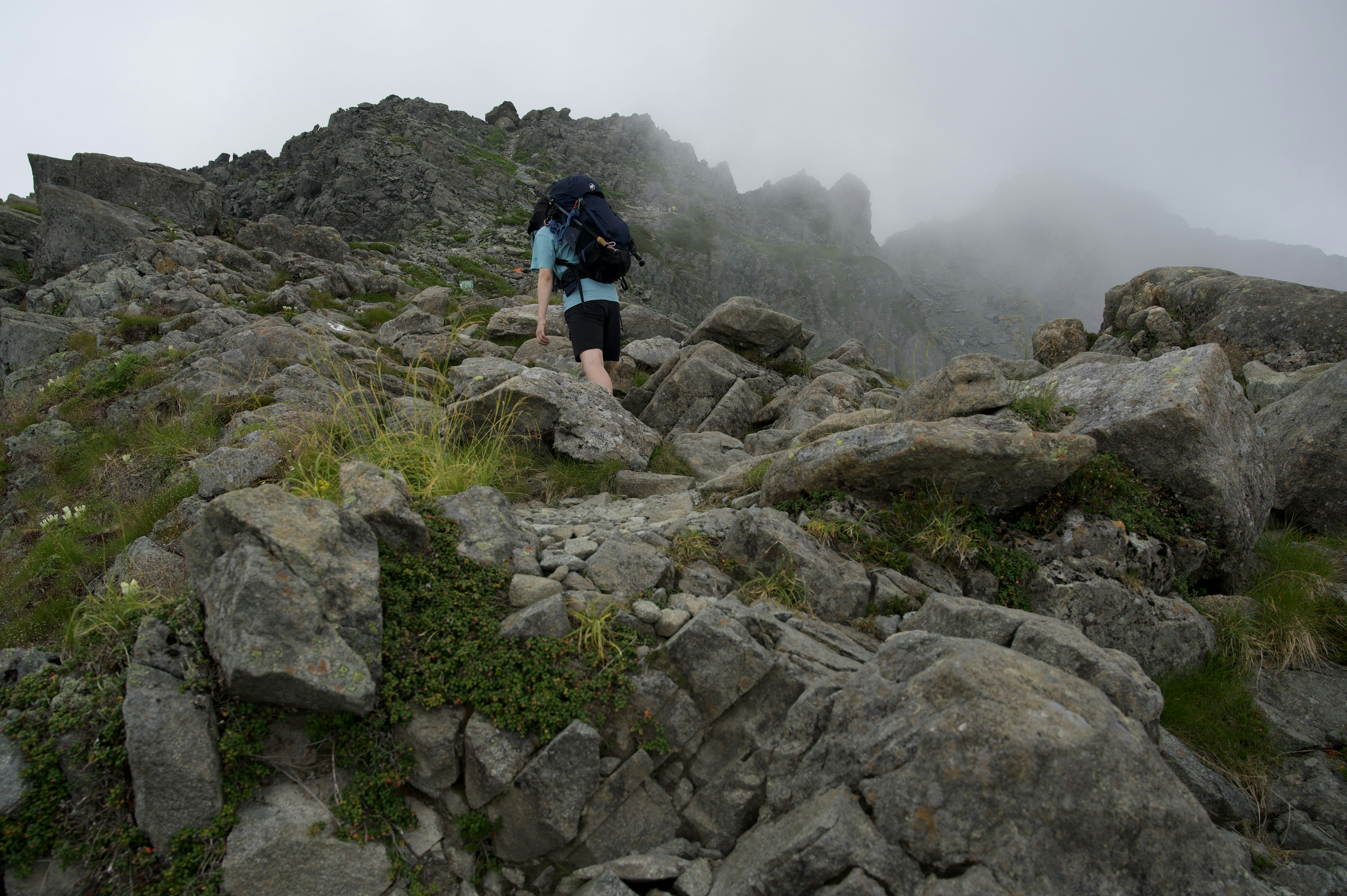 Hiker climbing a rocky mountain path shrouded in mist