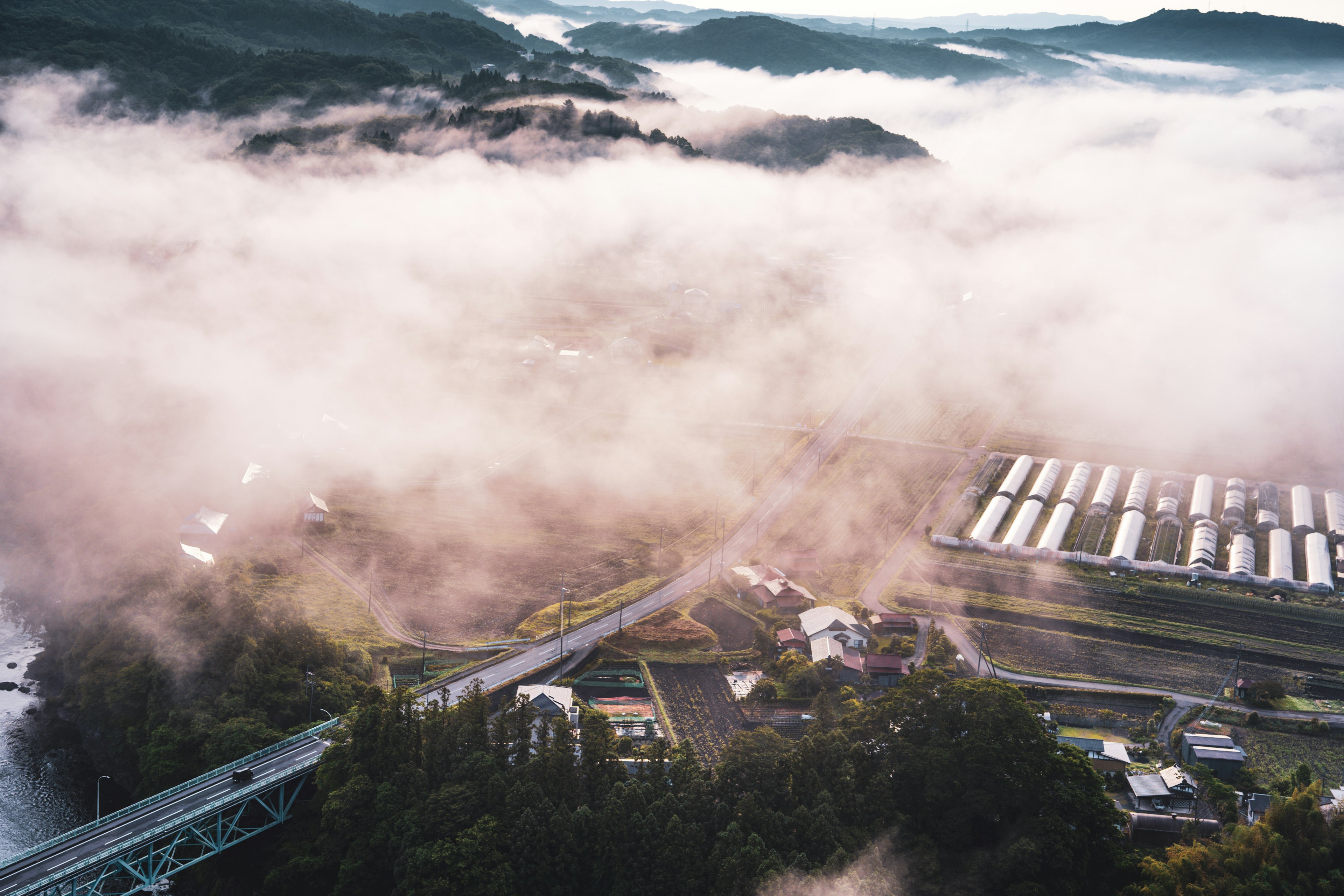 Aerial view of a misty landscape with a small village and mountains