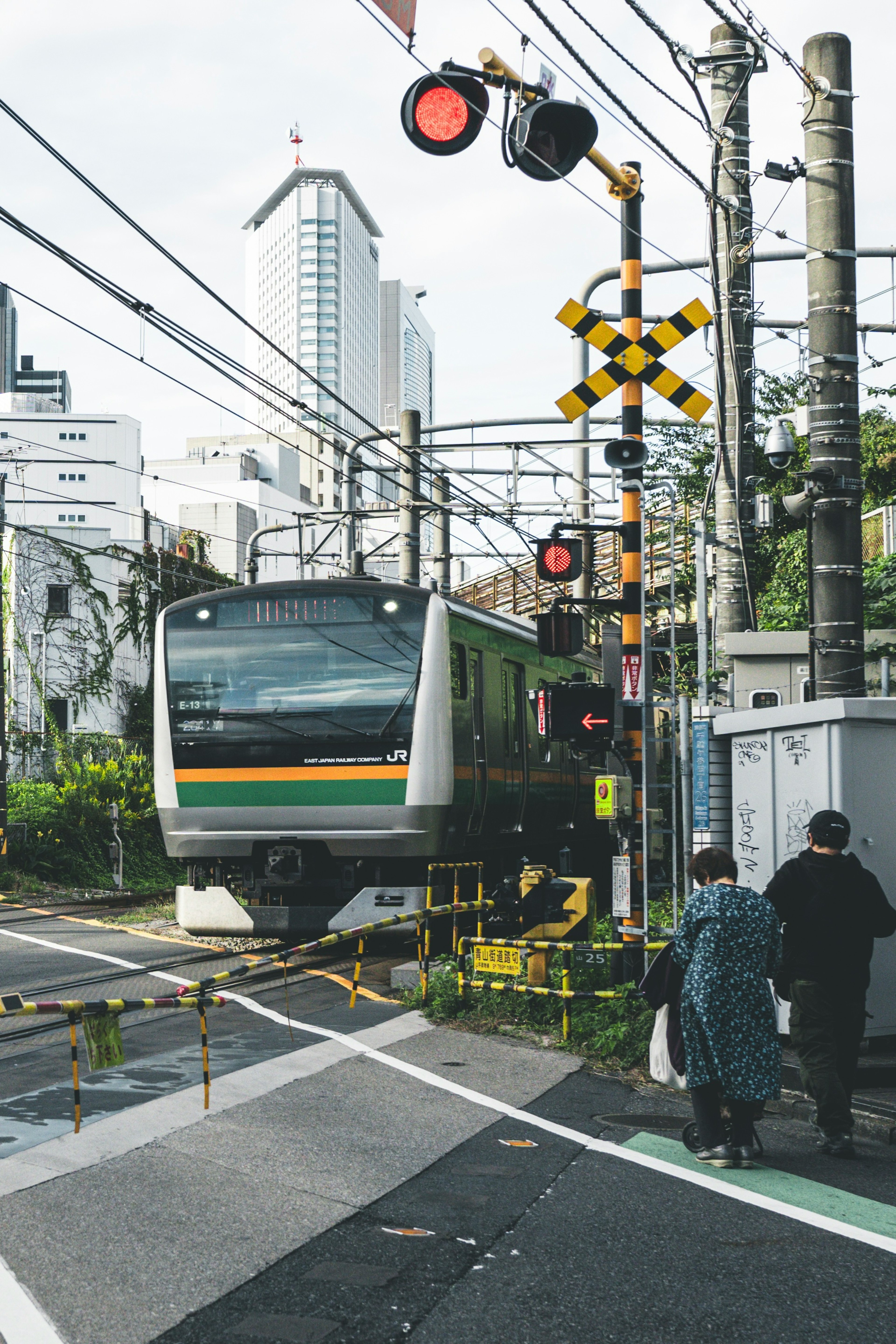 Train crossing in an urban setting with traffic signals and pedestrians