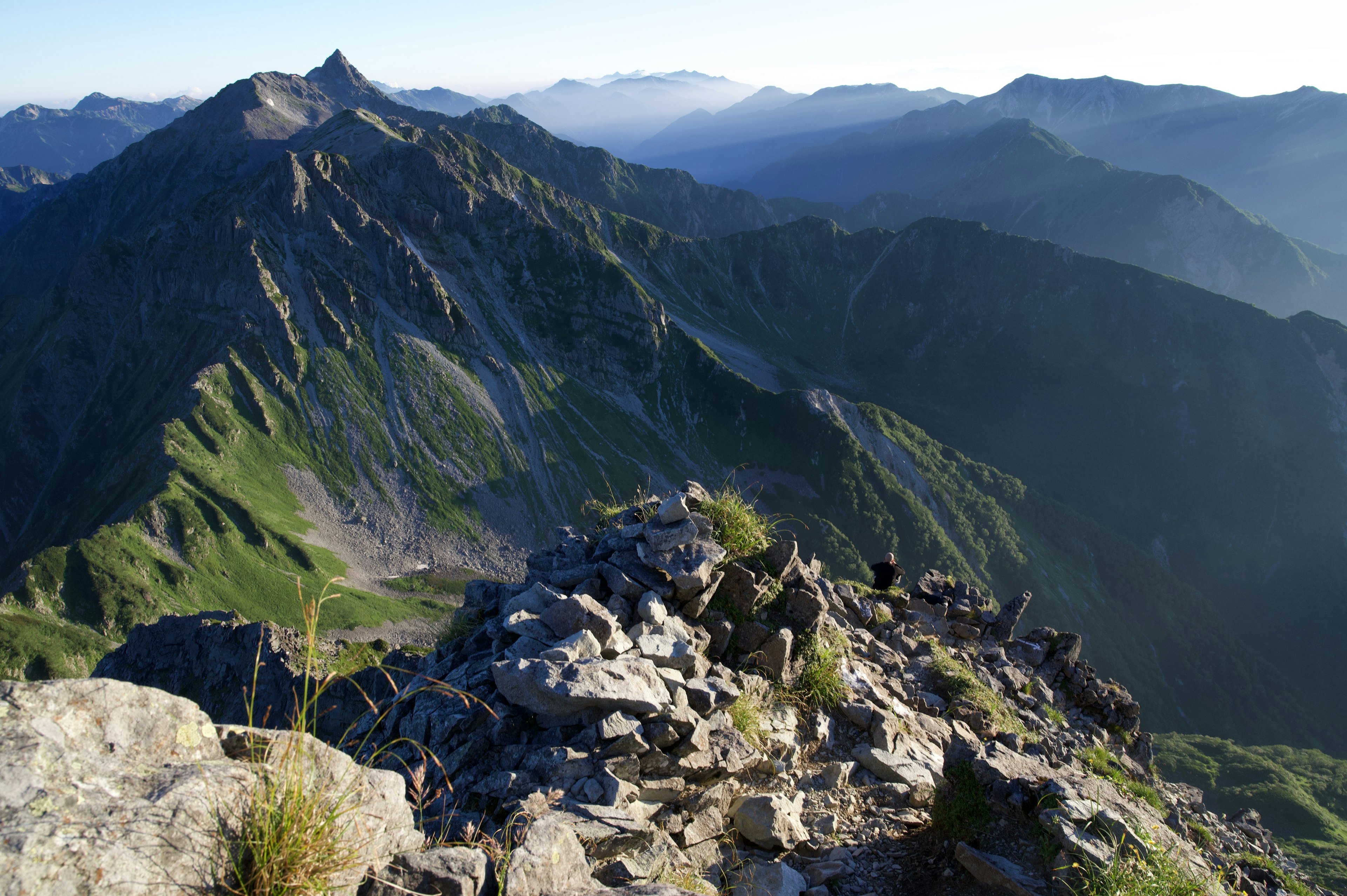 Vista panoramica dalla cima della montagna con pendii verdi e montagne lontane