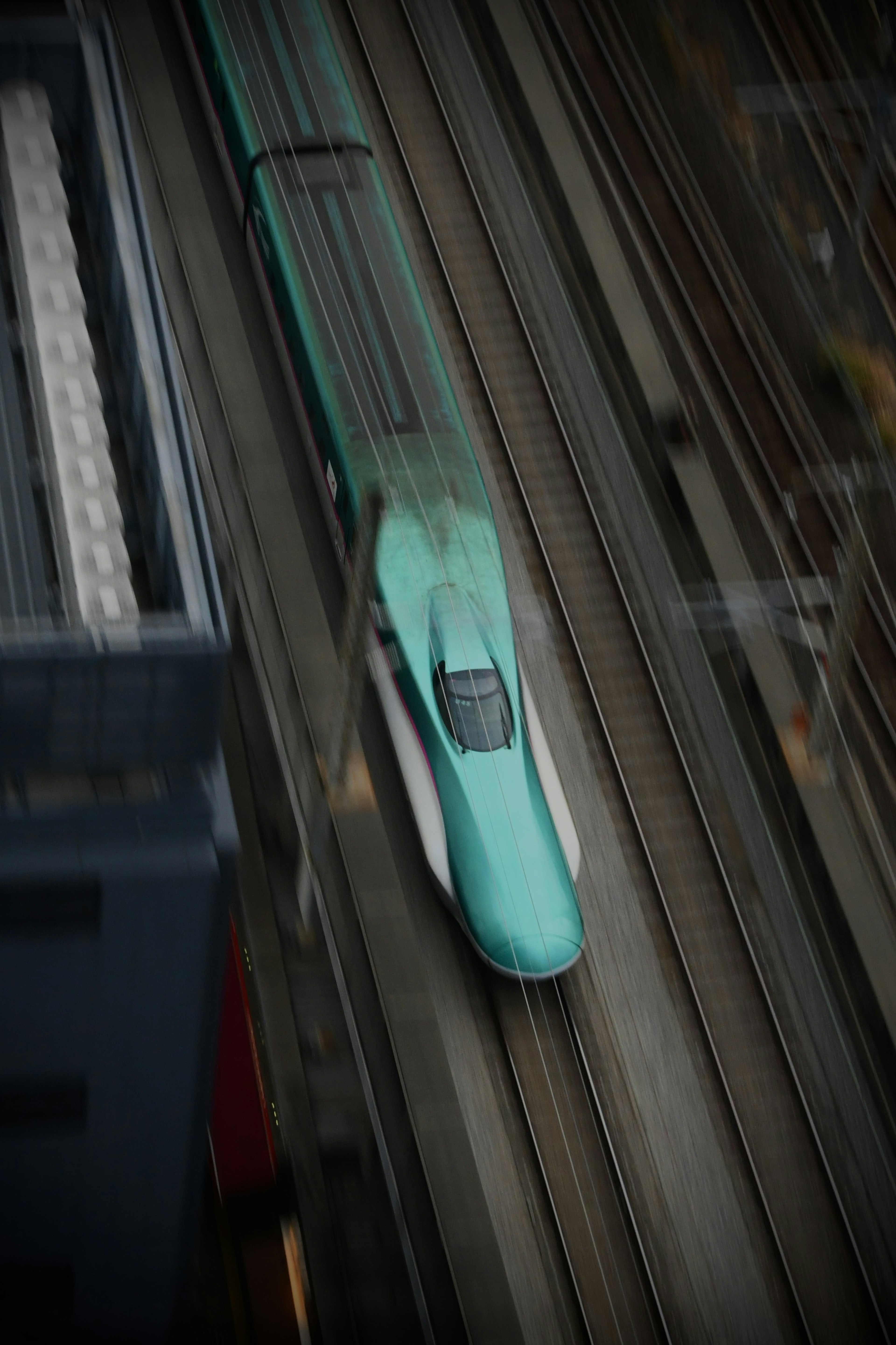 Aerial view of a green Shinkansen train traveling on tracks