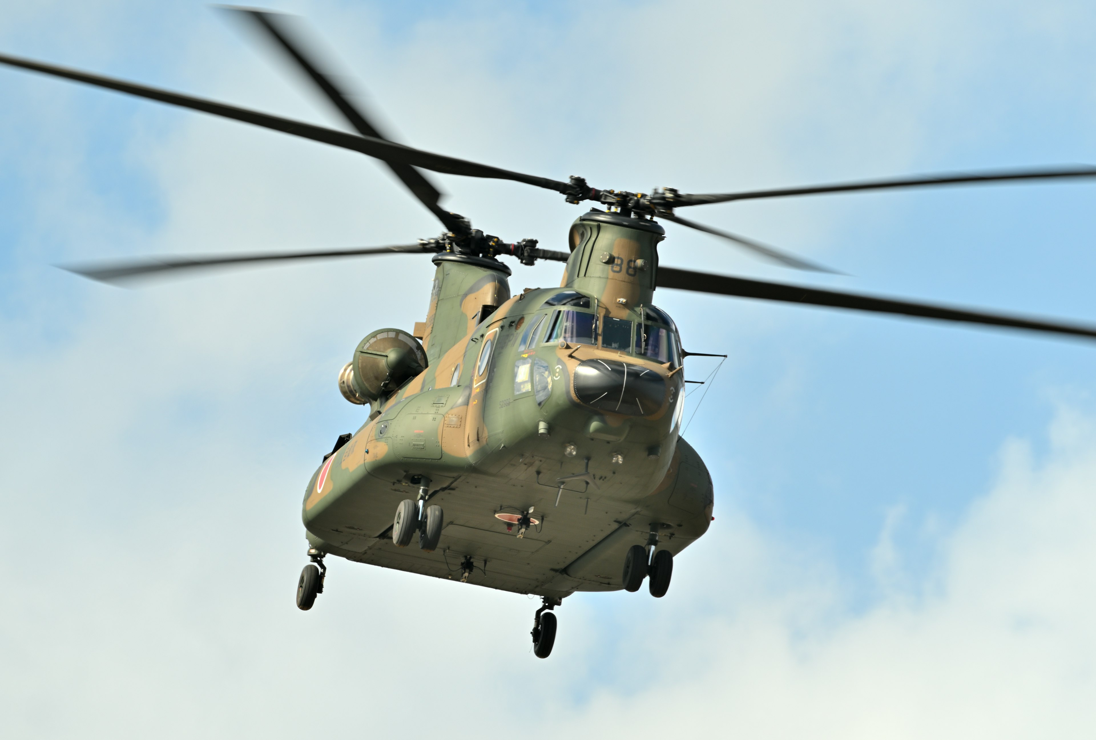 Military helicopter flying against a blue sky