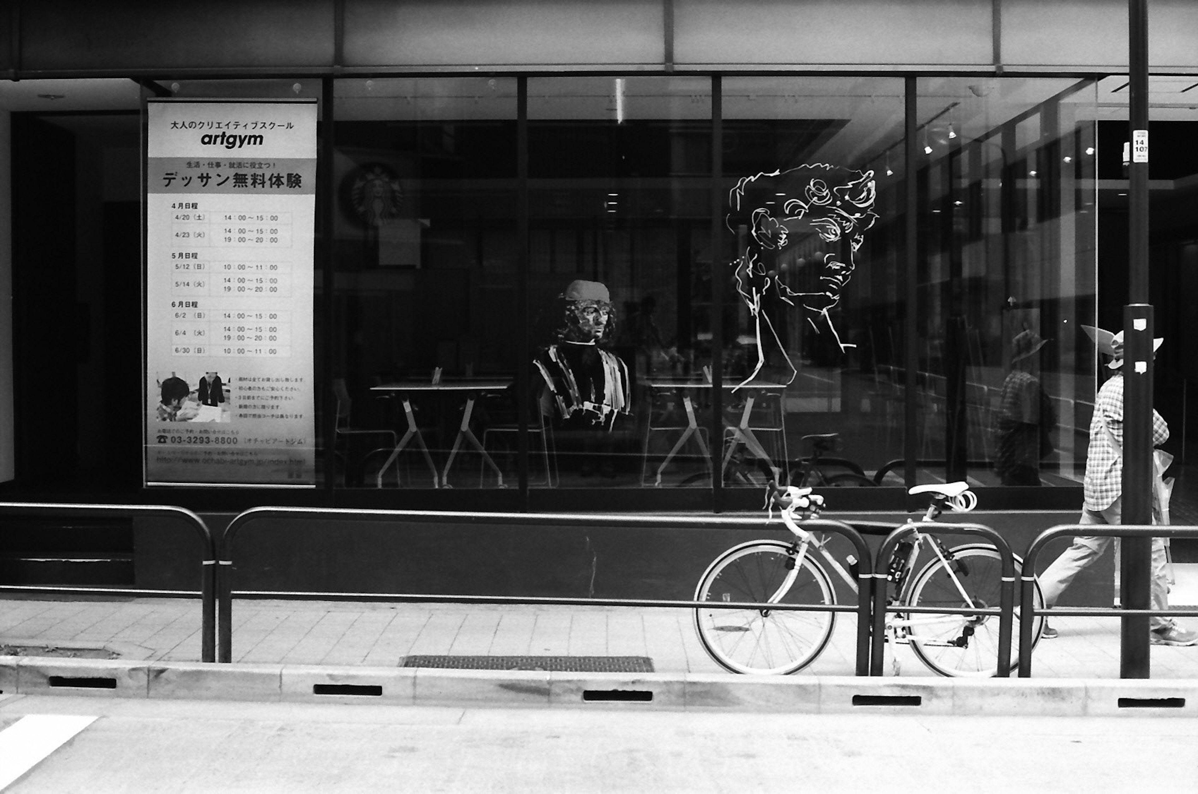 Imagen en blanco y negro de una persona sentada en la ventana de un café con la silueta de un transeúnte