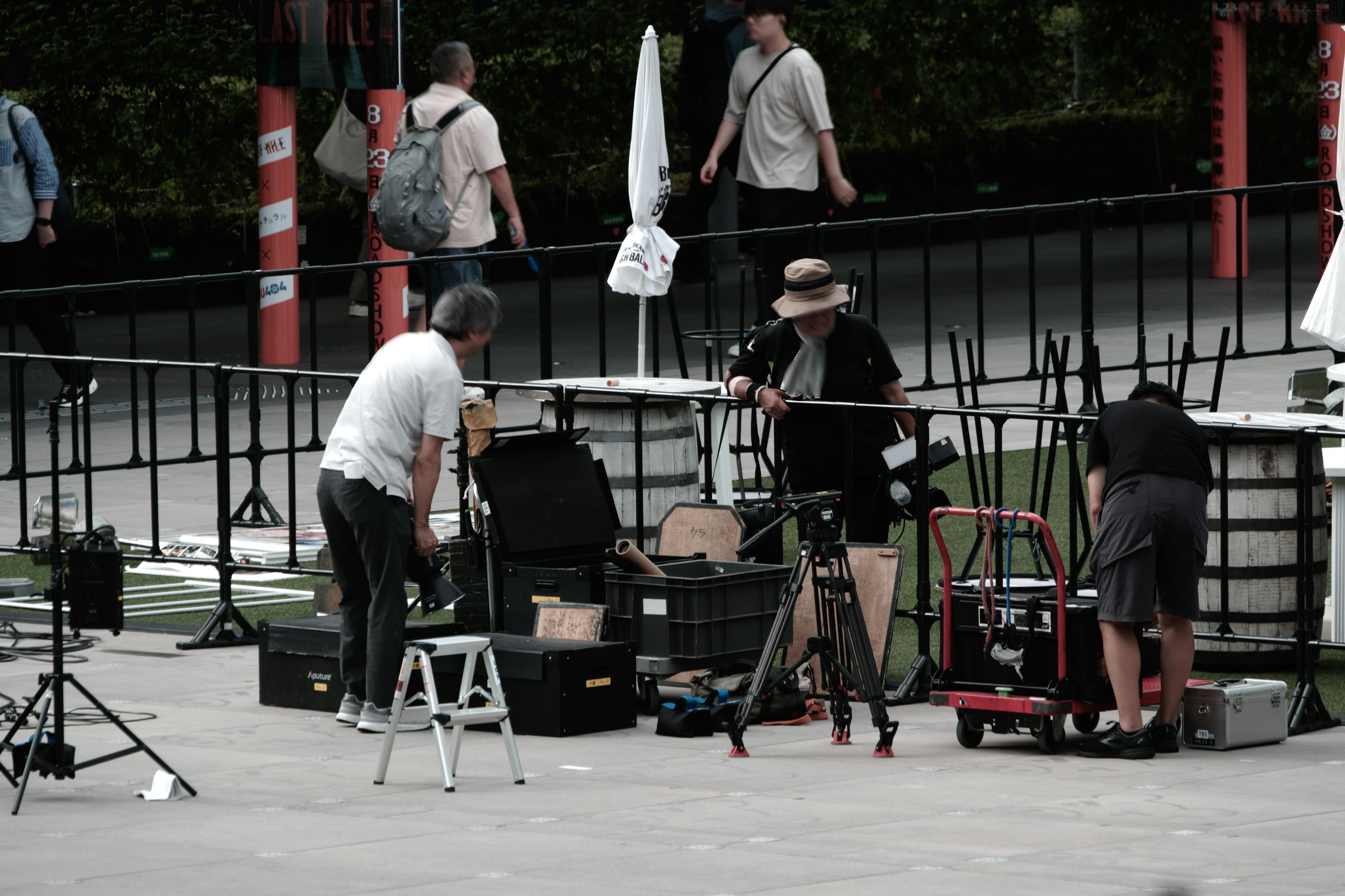 Crew setting up filming equipment with people in the background