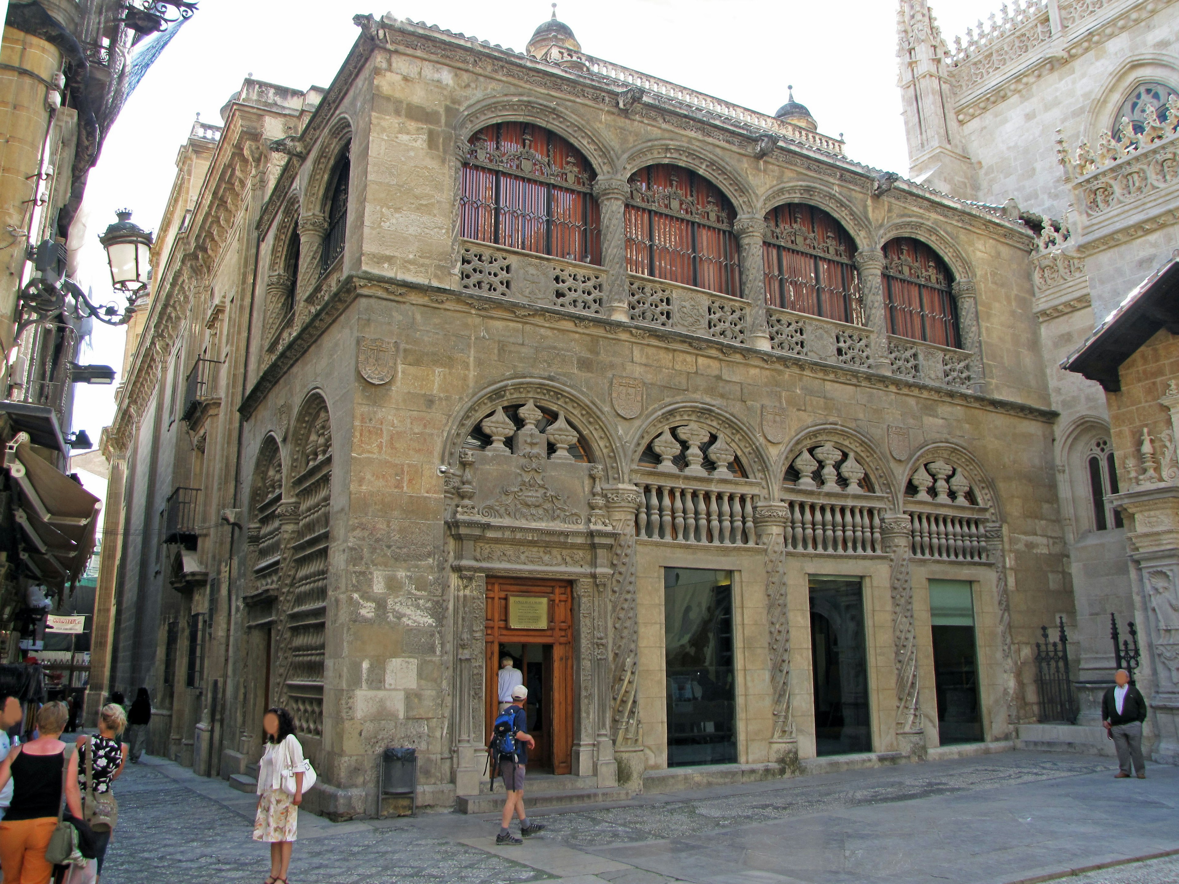 Exterior de un edificio histórico con fachada de piedra y ventanas decorativas