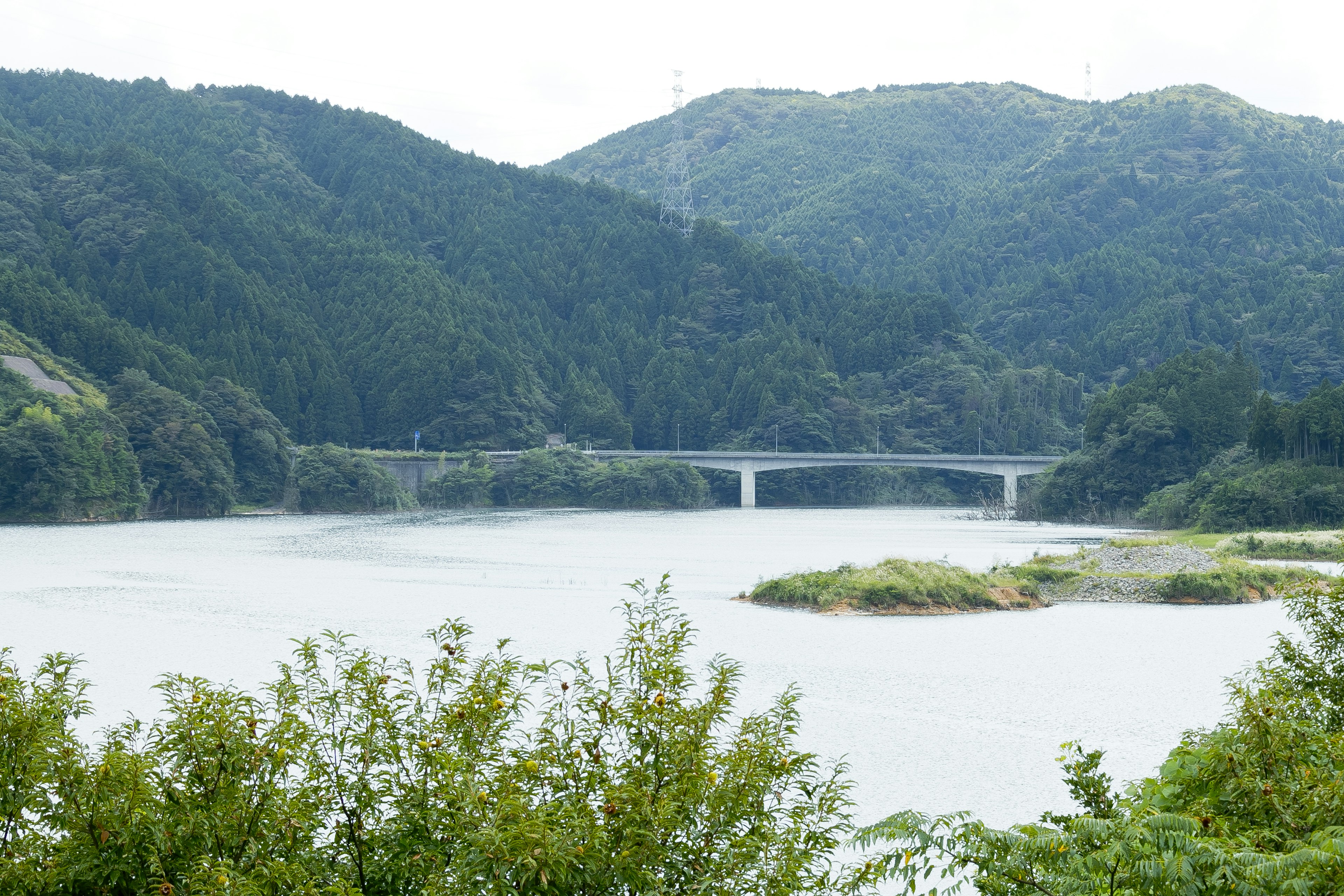 Malersicher Blick auf einen Fluss umgeben von Bergen mit einer Brücke