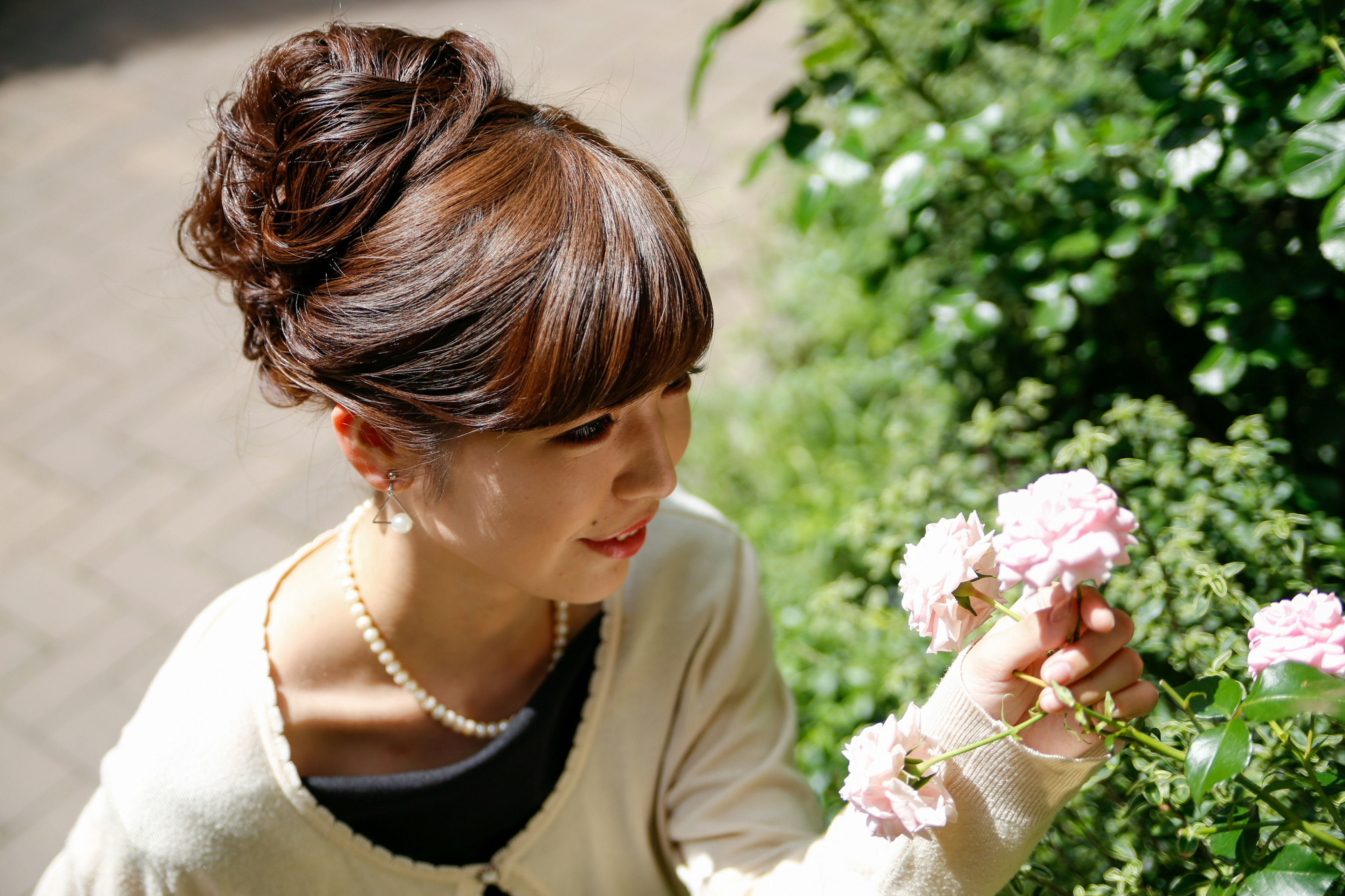 Frau, die lächelt und rosa Rosen in einem üppig grünen Hintergrund hält