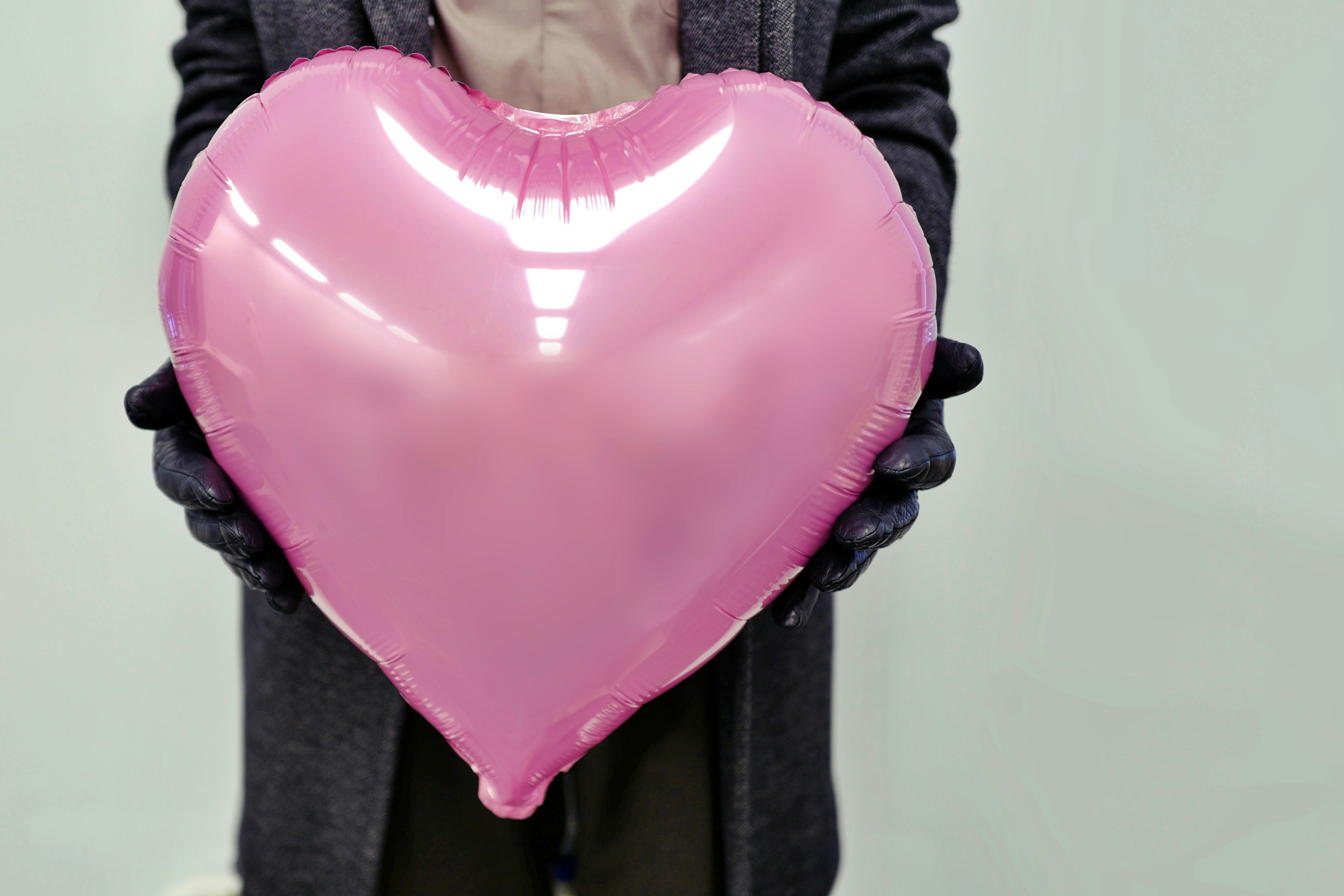 Persona che tiene un grande pallone a forma di cuore rosa