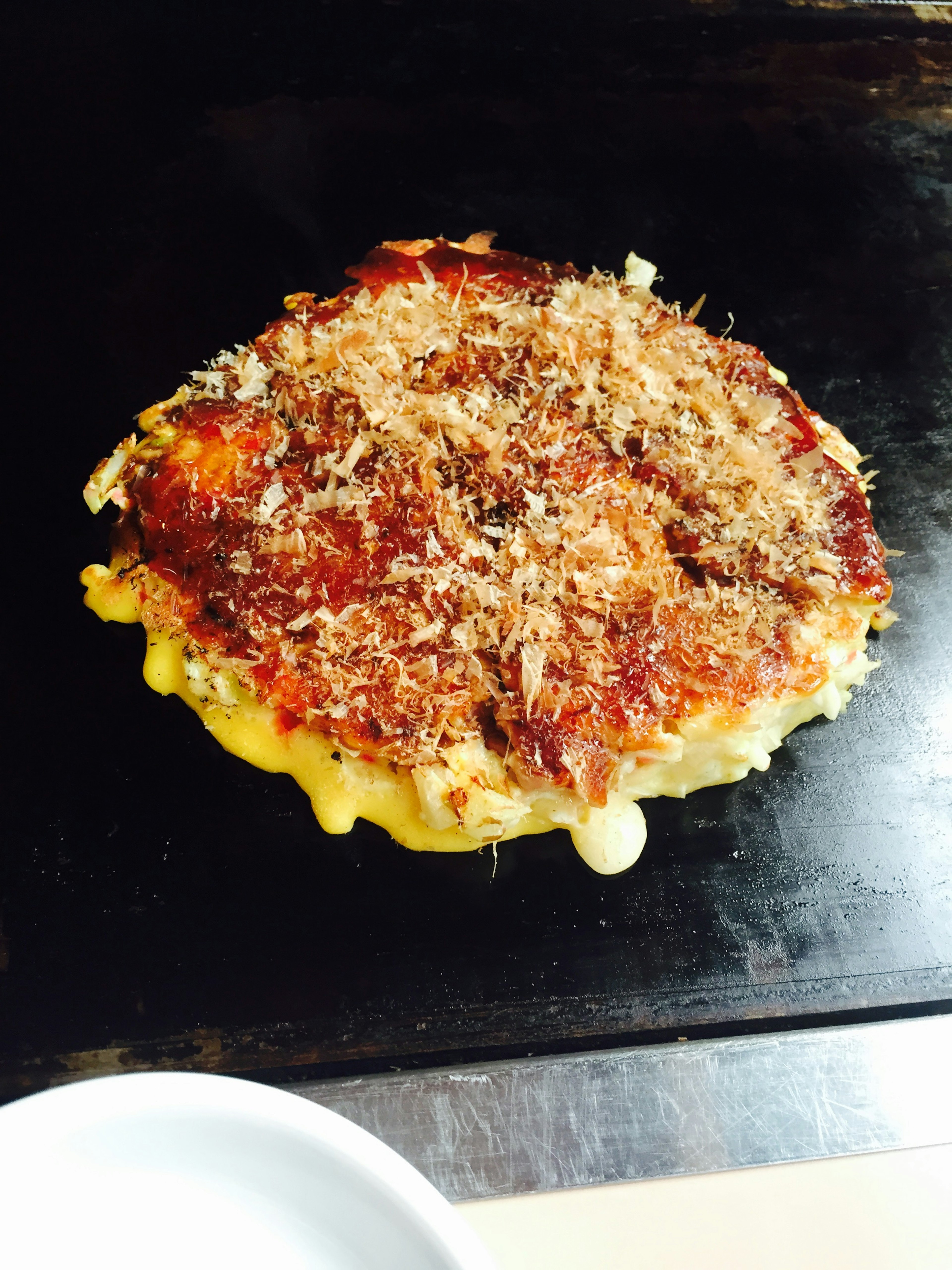 Okonomiyaki cooking on a hot griddle