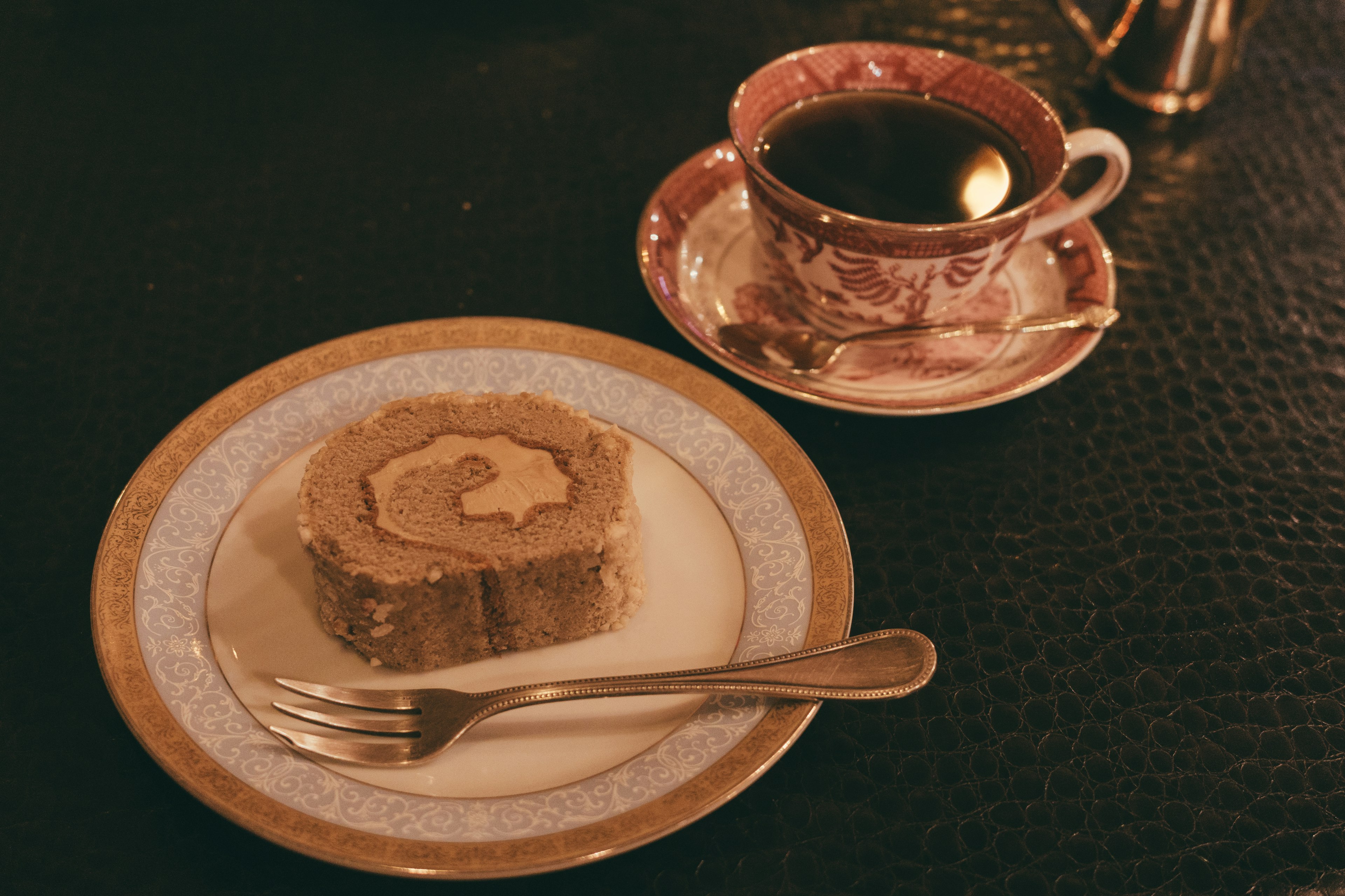 Ein Stück Biskuitrolle serviert mit Kaffee in einer eleganten Tasse und Untertasse warme Farben und gemütliche Atmosphäre