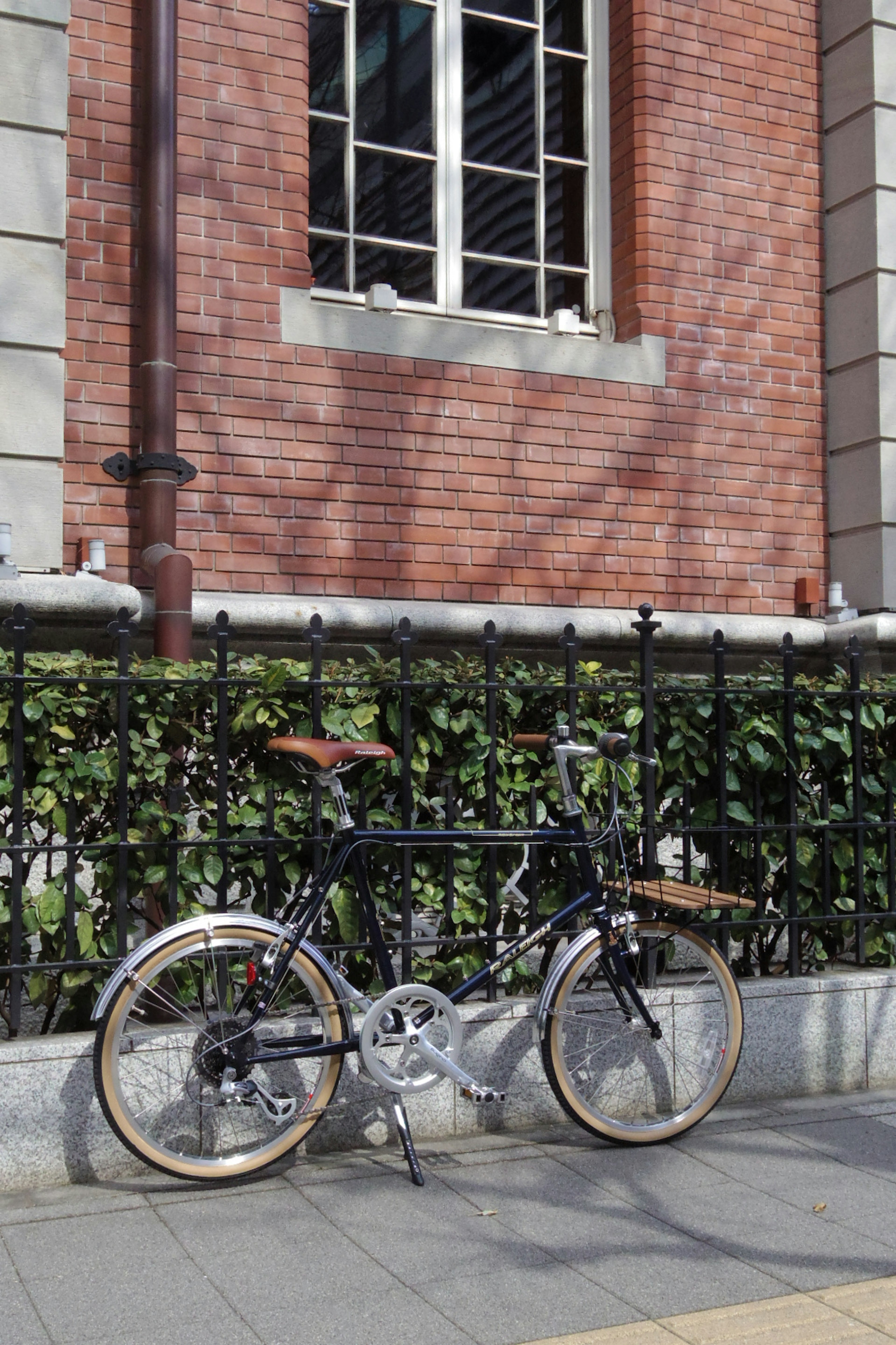 Bicicleta plegable estacionada frente a un edificio de ladrillo rojo