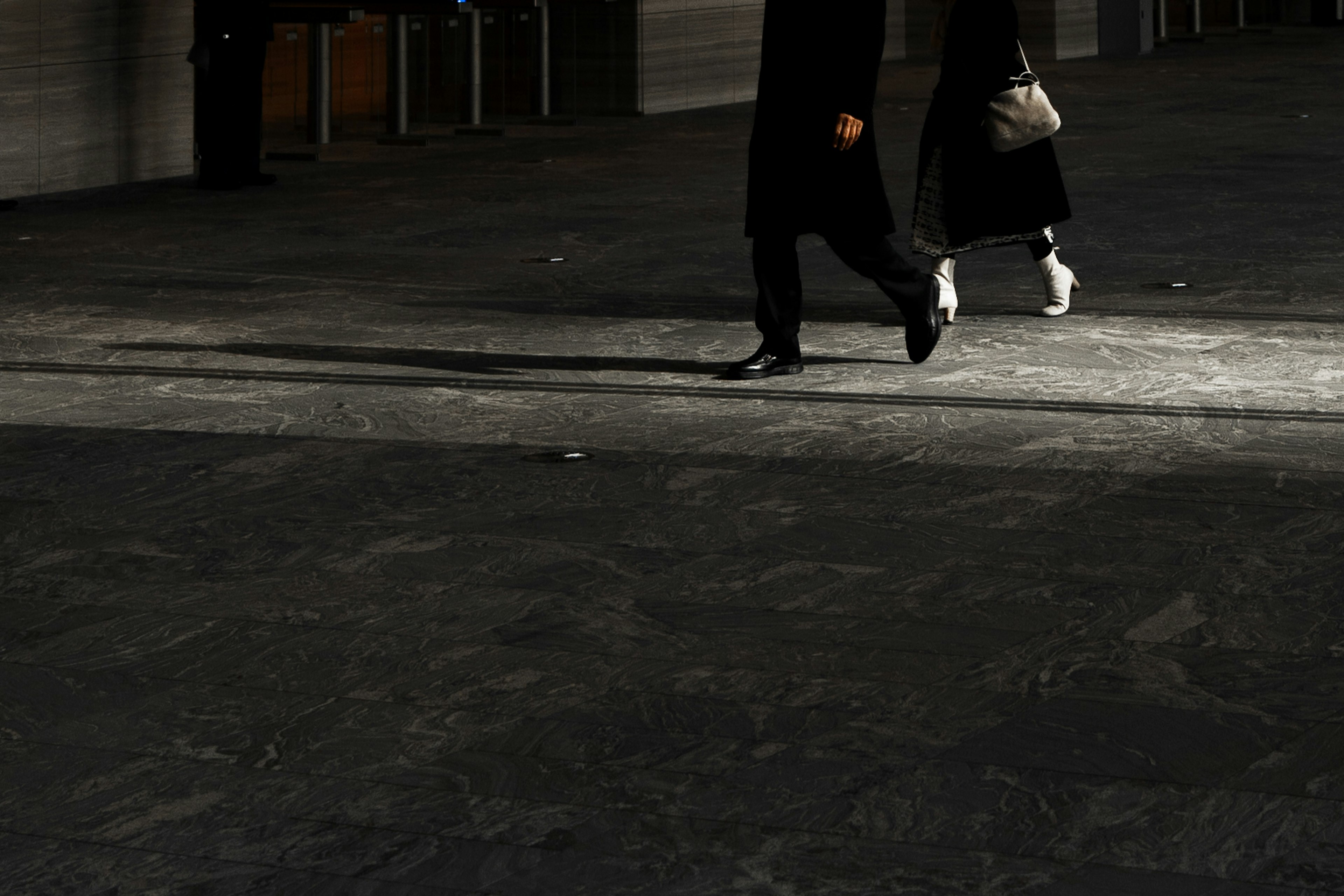 Two figures walking in a dark setting focusing on their feet