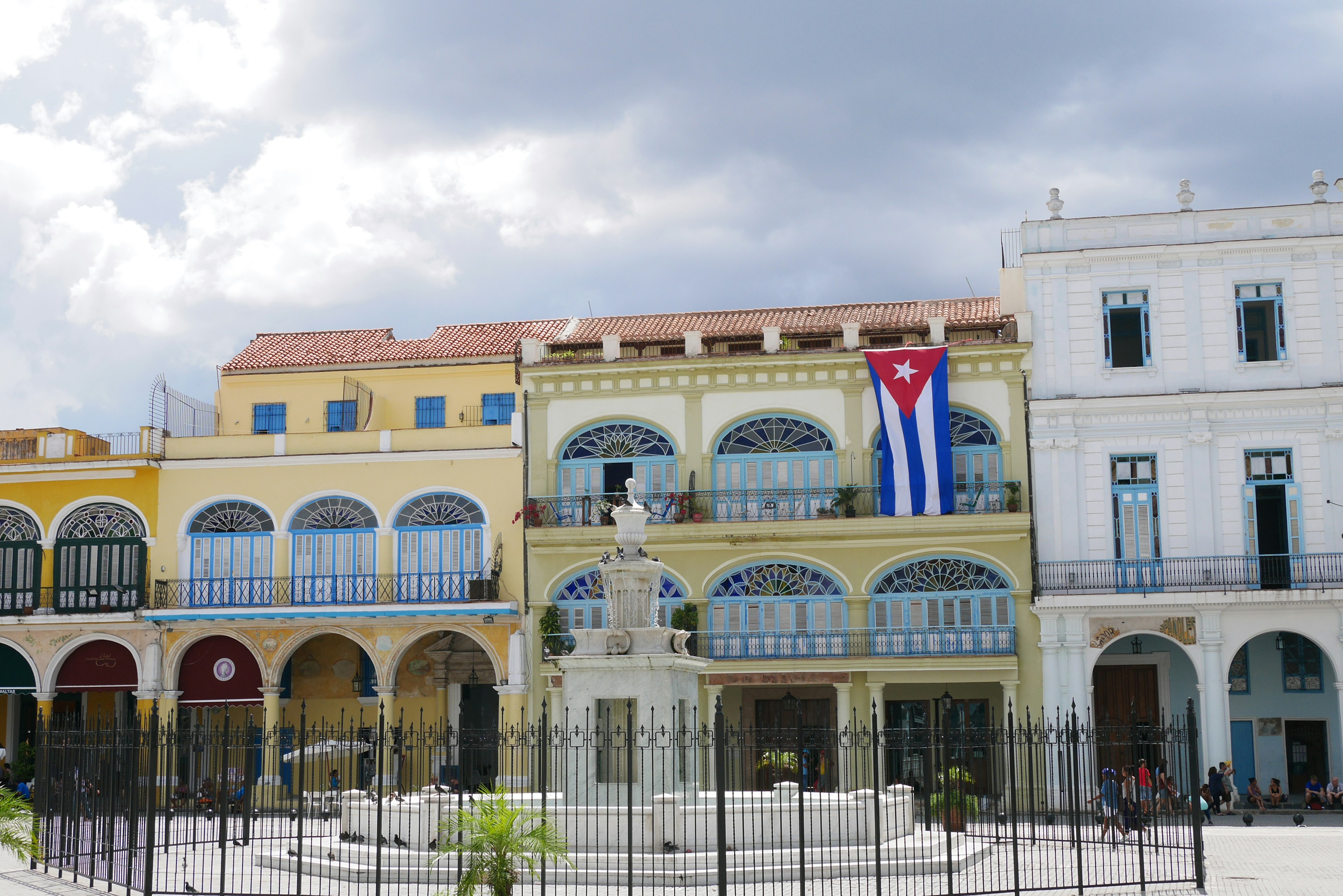 Colorful buildings lining a square with the Cuban flag displayed