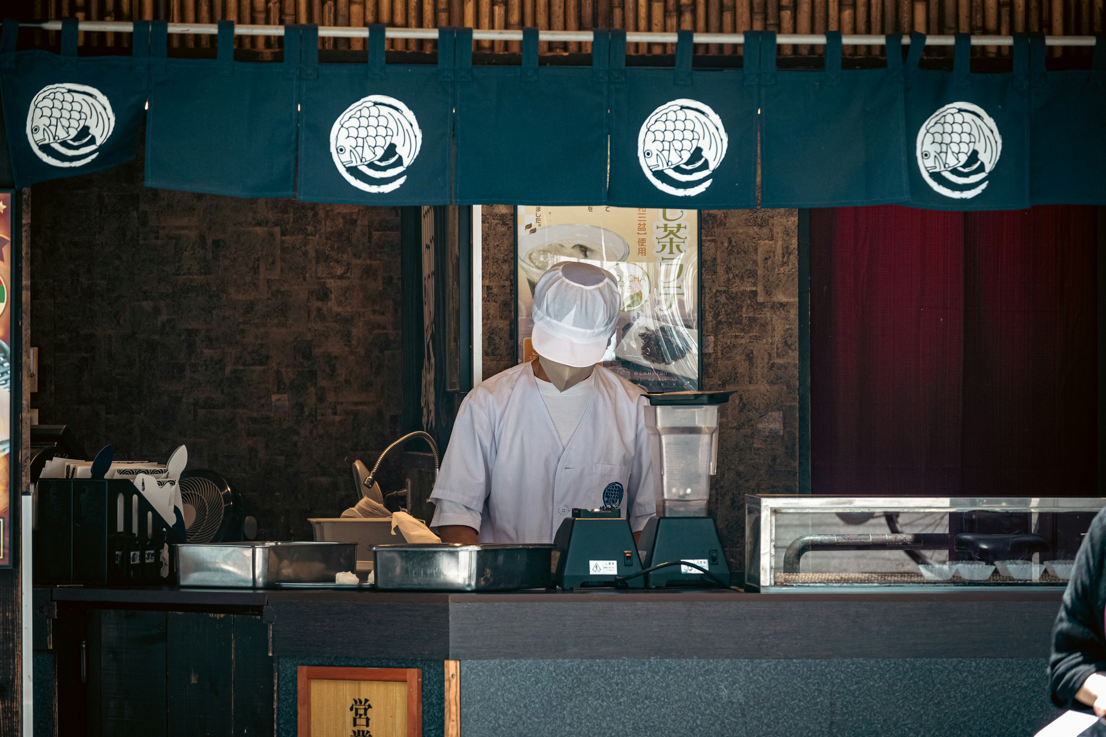 Chef préparant de la nourriture au comptoir portant un tablier blanc et un chapeau