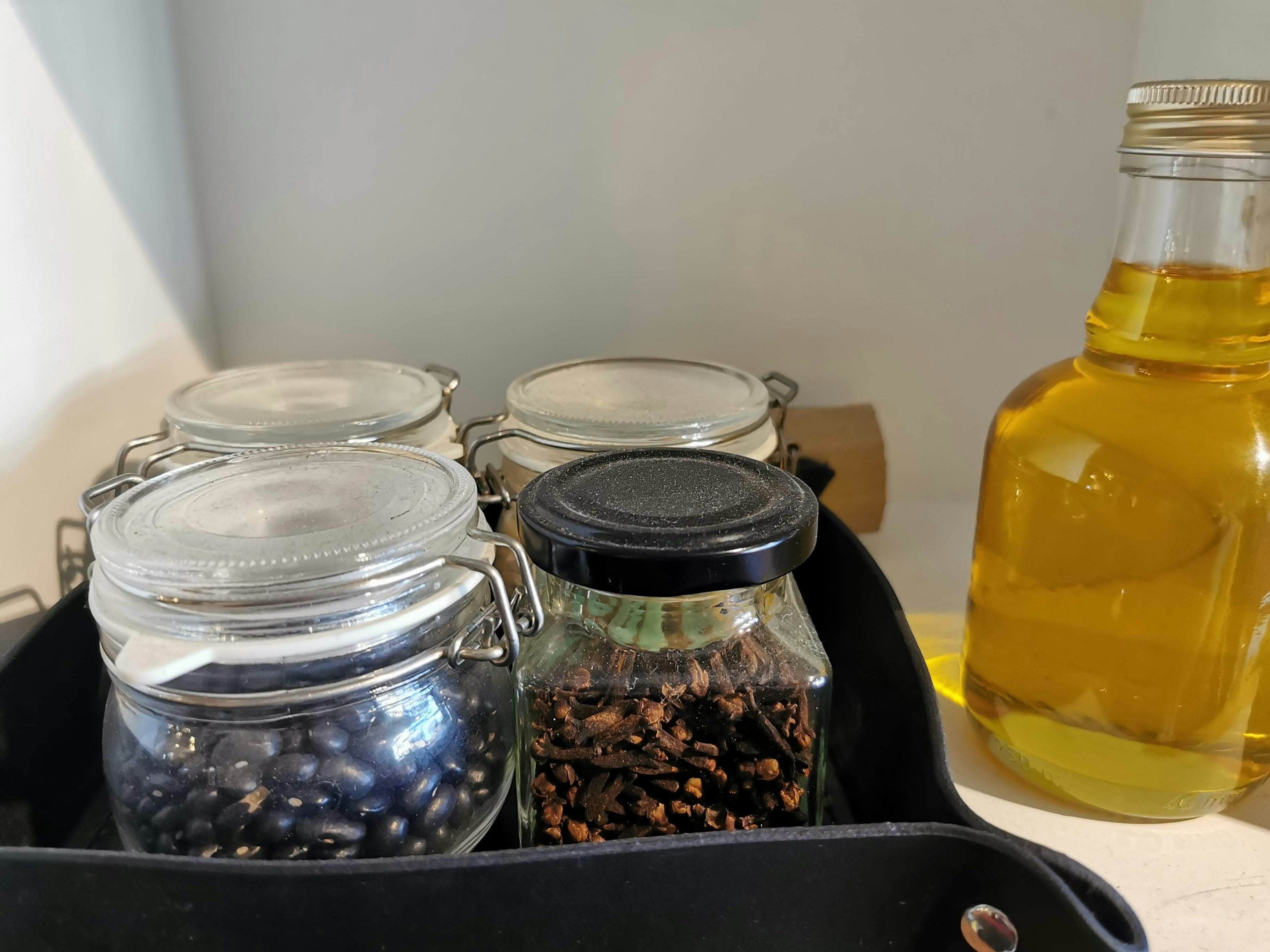 A corner of a kitchen with spice jars and a bottle of olive oil